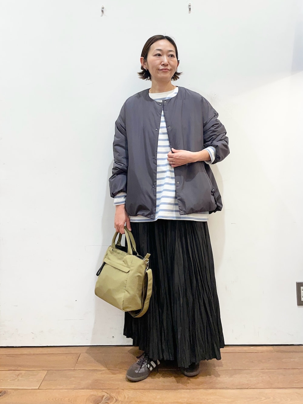 グレー系のブルゾン、ブラック系のスカート、ブルー系のTシャツ/カットソーを着用したレディースの冬コーディネートの2枚目の写真