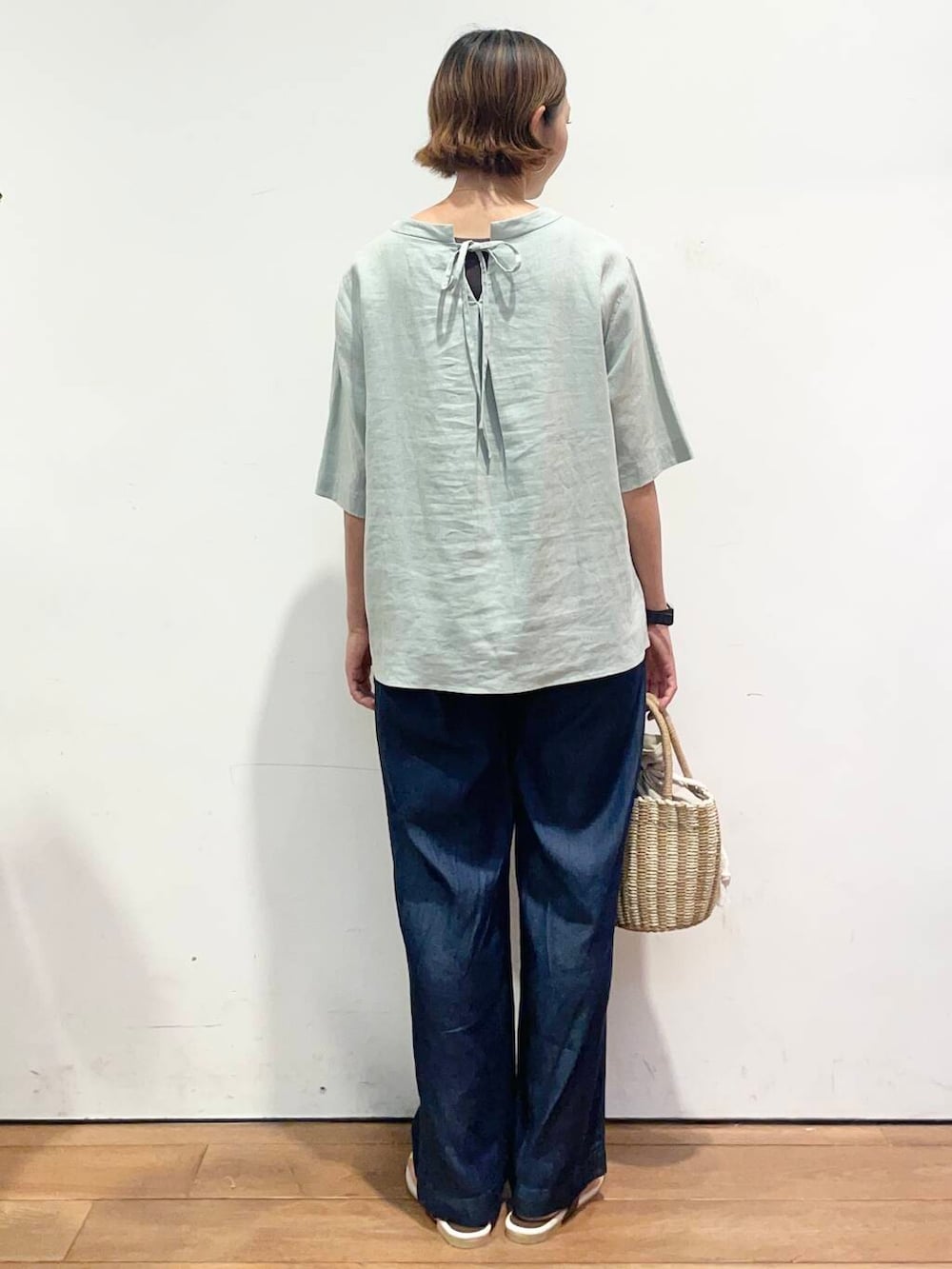 グレー系のハンドバッグ、ブラウン系のサンダル、ブルー系のデニムパンツを着用したレディースの夏コーディネートの5枚目の写真