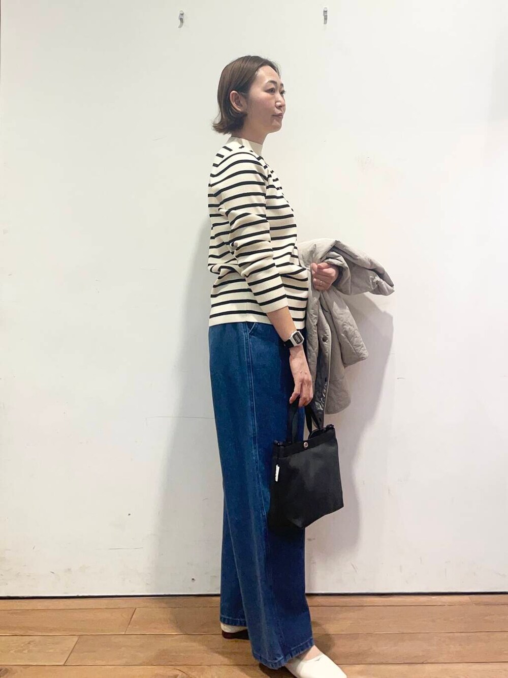 ブルー系のデニムパンツ、グレー系のダウンジャケット/コート、ブラック系のニット/セーターを着用したレディースの春コーディネートの8枚目の写真