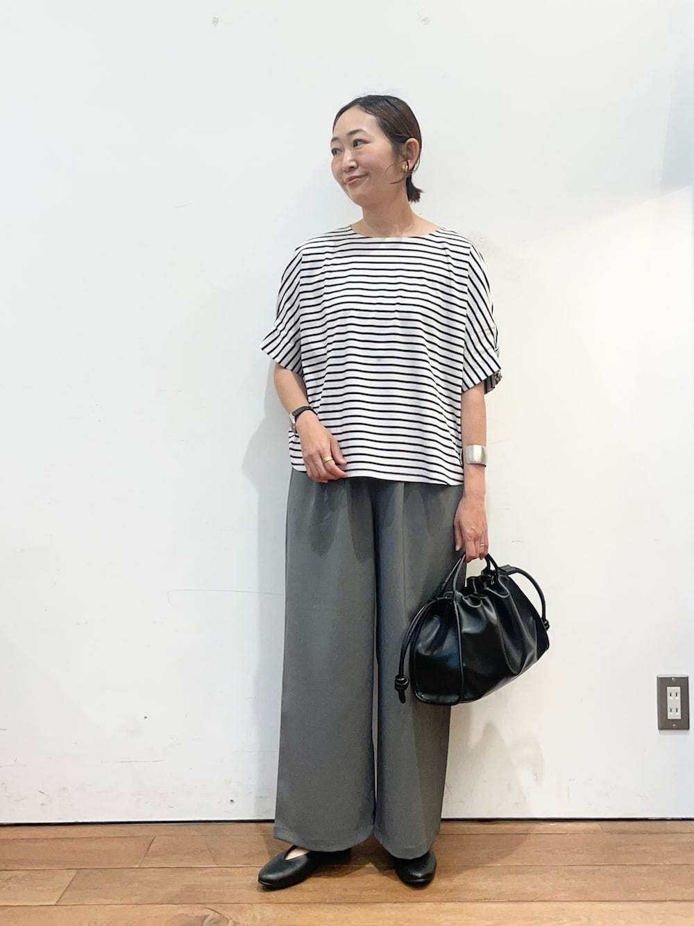 ホワイト系のTシャツ/カットソー、ブラック系のパンプス、ブラック系のトートバッグを着用したレディースの春コーディネートの2枚目の写真