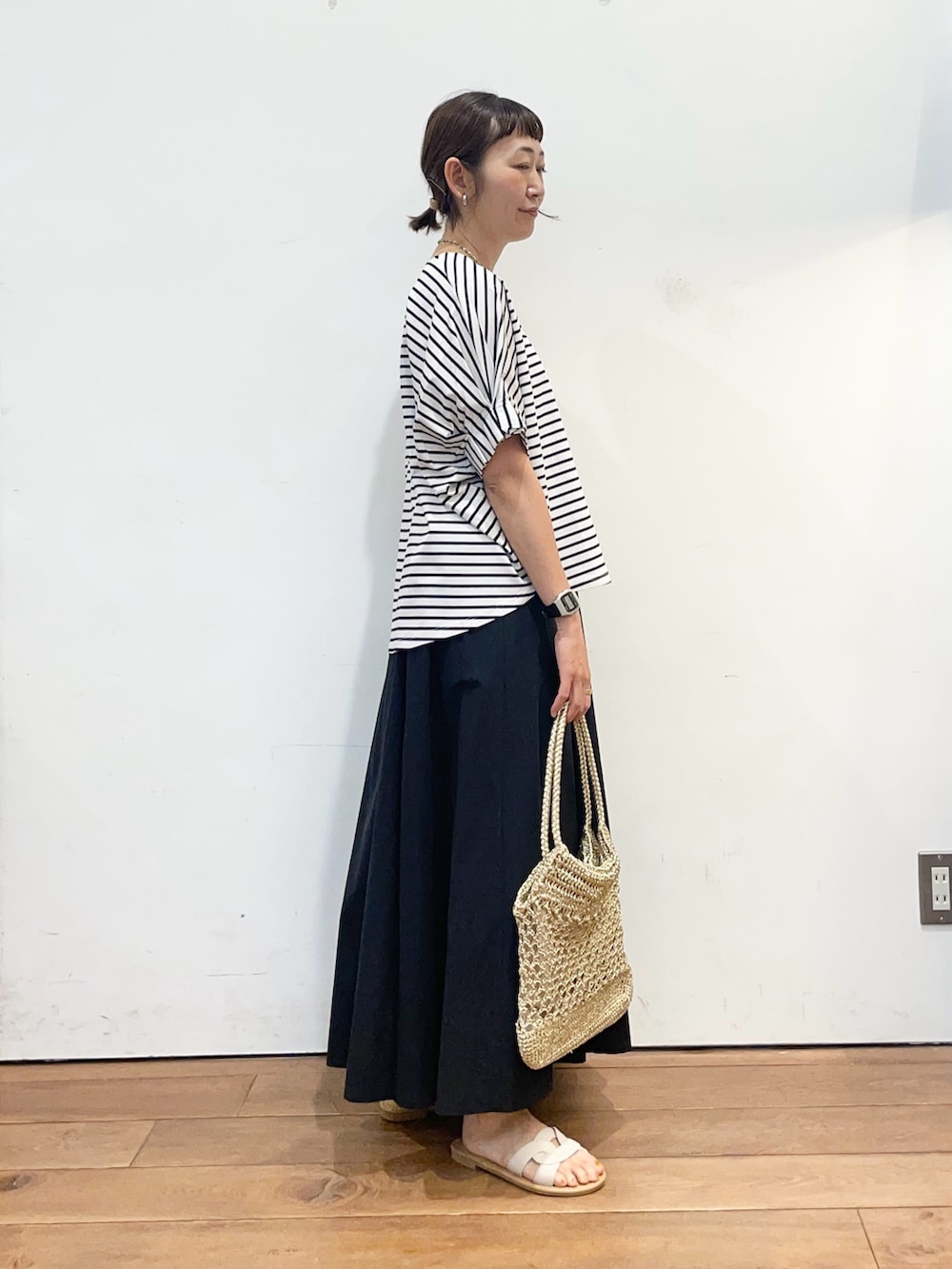 ホワイト系のTシャツ/カットソー、ブラック系のスカート、ホワイト系のサンダルを着用したレディースの夏コーディネートの3枚目の写真