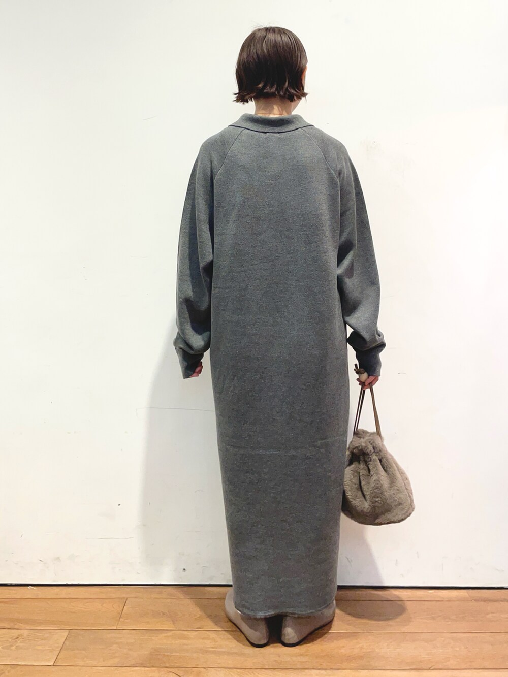 グレー系のワンピース、ブラウン系のショルダーバッグ、ベージュ系のパンプスを着用したレディースの秋コーディネートの4枚目の写真