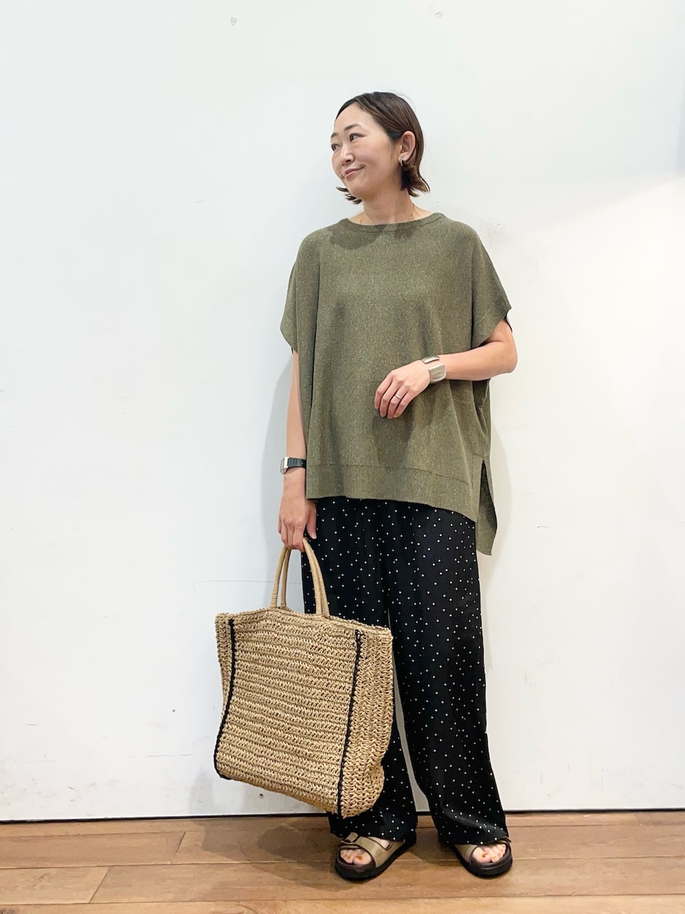 グリーン系のニット/セーター、ブラック系のその他パンツ、ベージュ系のトートバッグを着用したレディースの春コーディネートの2枚目の写真