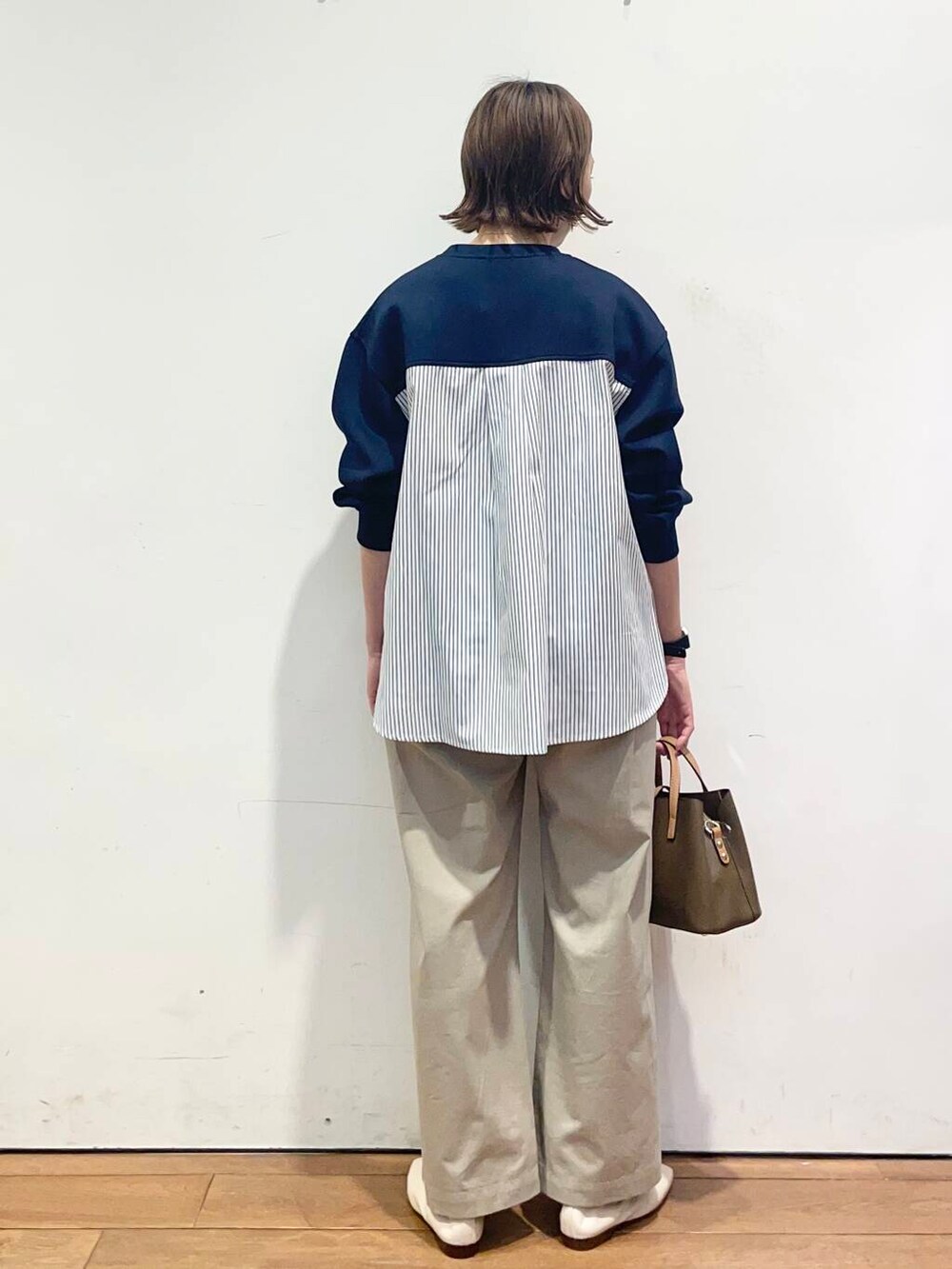 ブラウン系のハンドバッグ、ブルー系のその他トップス、ホワイト系のバレエシューズを着用したレディースの春コーディネートの4枚目の写真