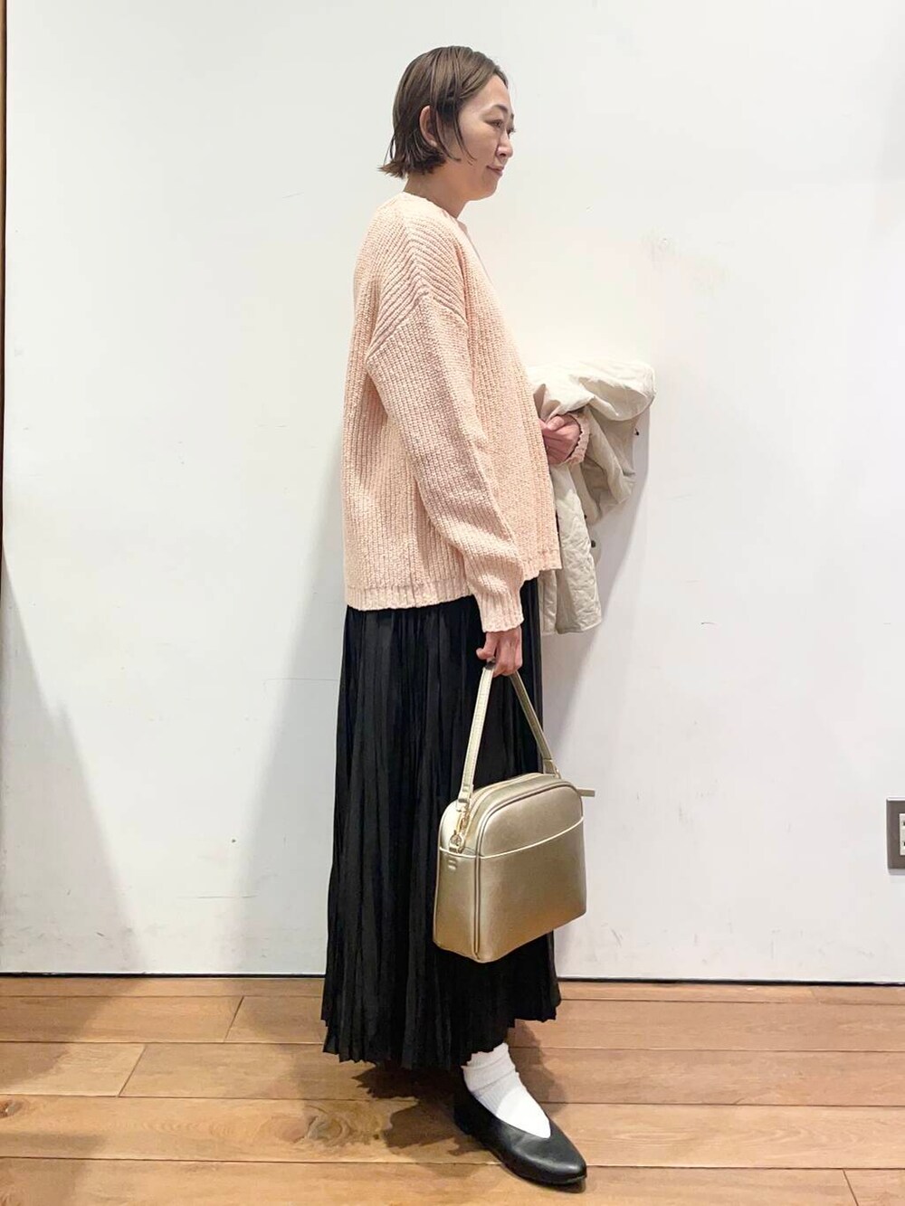 ゴールド系のショルダーバッグ、ブラック系のパンプス、ホワイト系のダウンジャケット/コートを着用したレディースの冬コーディネートの6枚目の写真