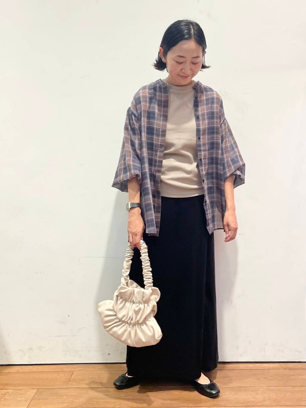 ホワイト系のハンドバッグ、ブラック系のワンピース、ブラック系のスカートを着用したレディースの秋コーディネートの3枚目の写真