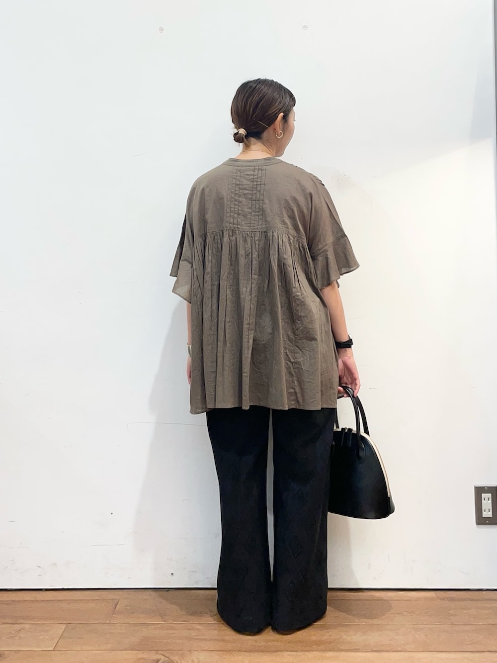 グリーン系のシャツ/ブラウス、ブラック系のその他パンツ、ブラック系のハンドバッグを着用したレディースの秋コーディネートの4枚目の写真