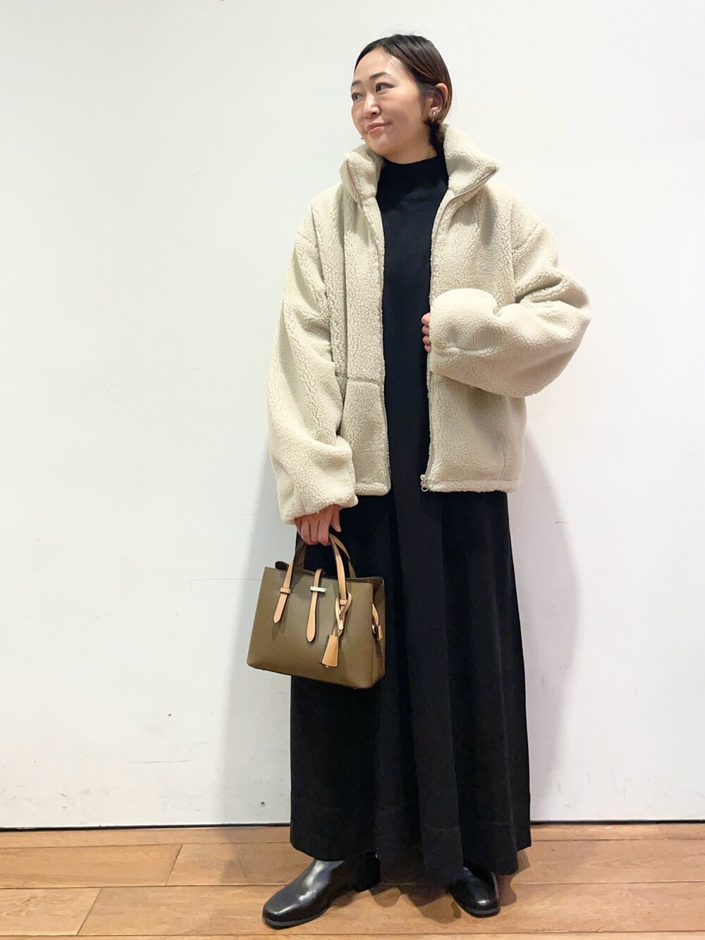 ホワイト系のその他アウター、ブラウン系のハンドバッグ、ブラック系のワンピースを着用したレディースの冬コーディネートの2枚目の写真