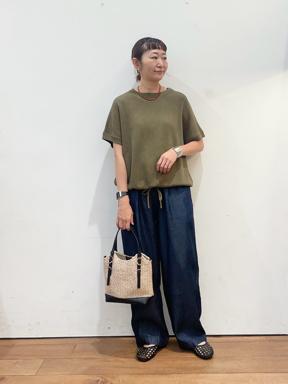 グリーン系のニット/セーター、ブルー系のデニムパンツ、ブラック系のサンダルを着用したレディースの夏コーディネートの2枚目の写真