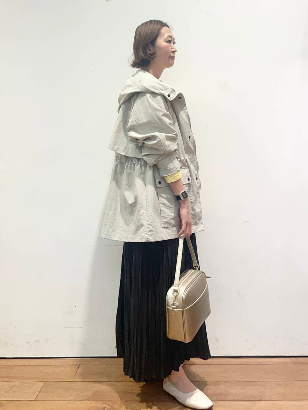 ゴールド系のショルダーバッグ、ブラック系のスカート、ホワイト系のバレエシューズを着用したレディースの春コーディネートの3枚目の写真