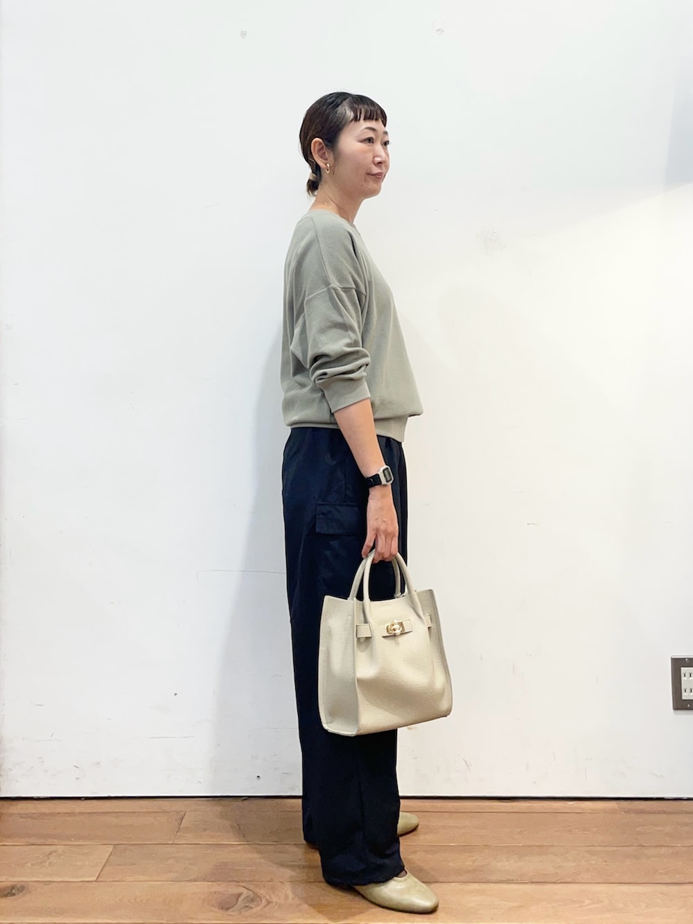 グリーン系のTシャツ/カットソー、グレー系のハンドバッグ、ブラウン系のスリッポンを着用したレディースの秋コーディネートの3枚目の写真