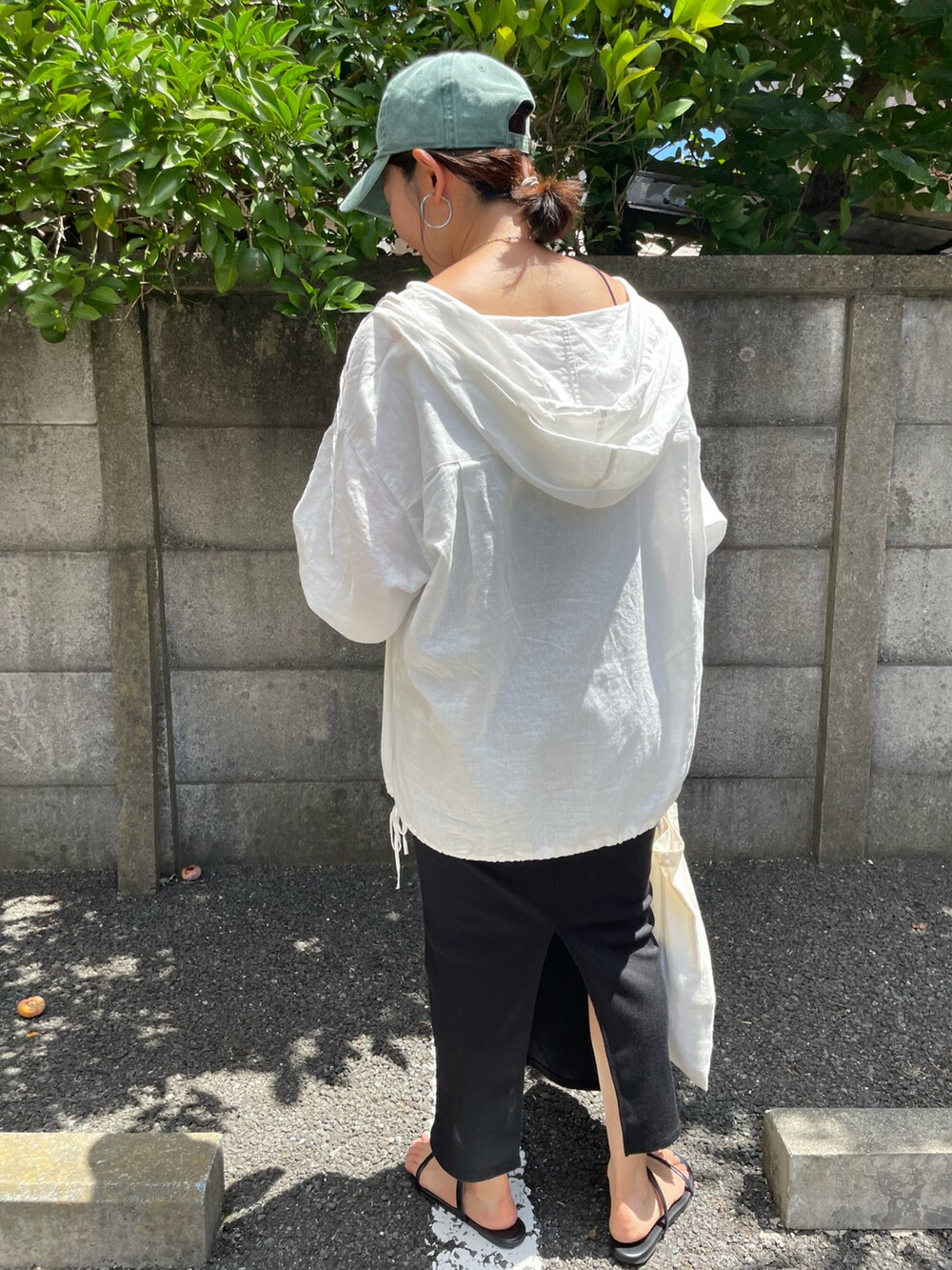 ブラック系のサンダル、ホワイト系のパーカー、グリーン系のキャップを着用したレディースの夏コーディネートの4枚目の写真