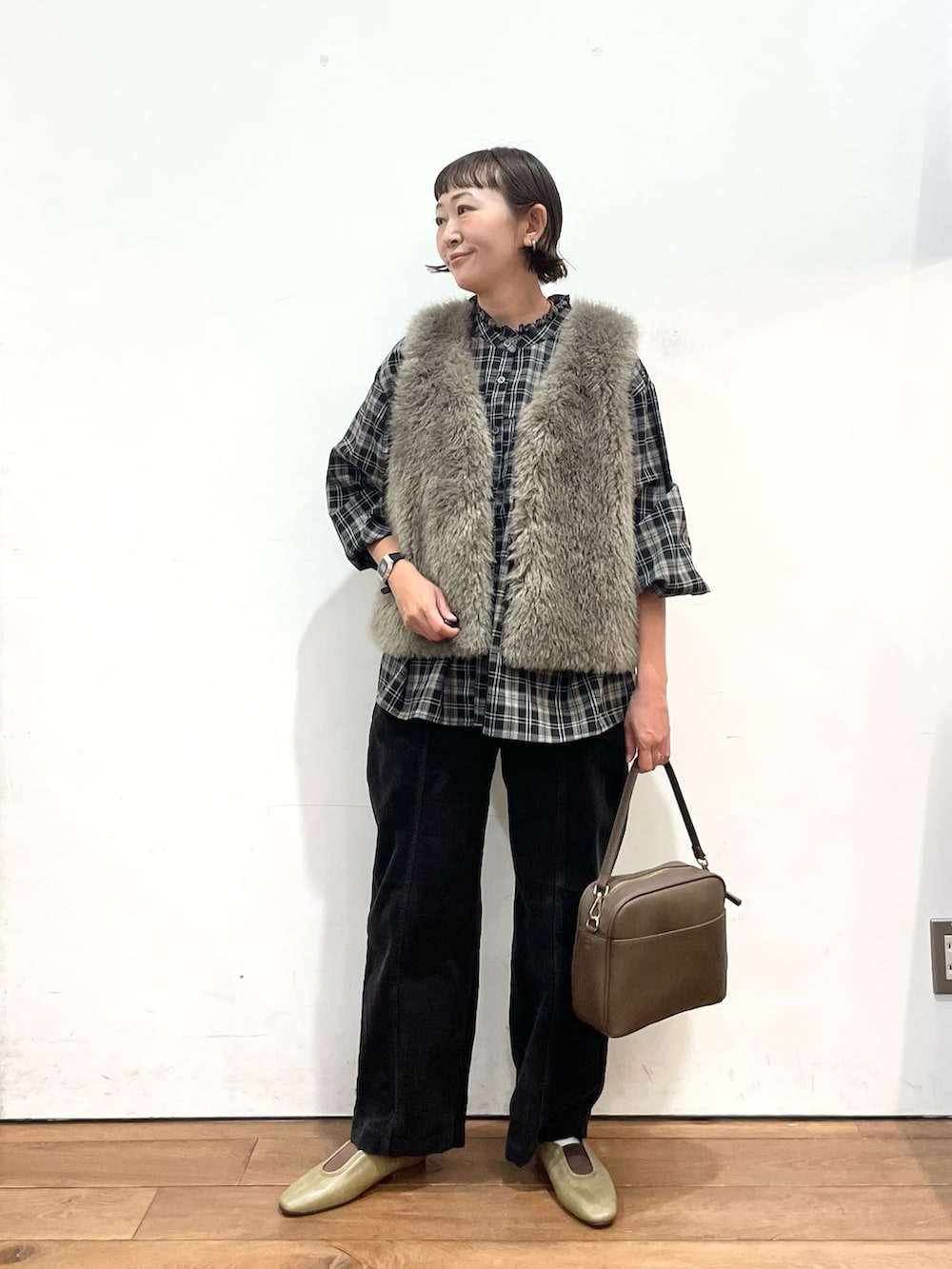 グレー系のダウンベスト、ブラック系のシャツ/ブラウス、グレー系のその他パンツを着用したレディースの秋コーディネートの2枚目の写真