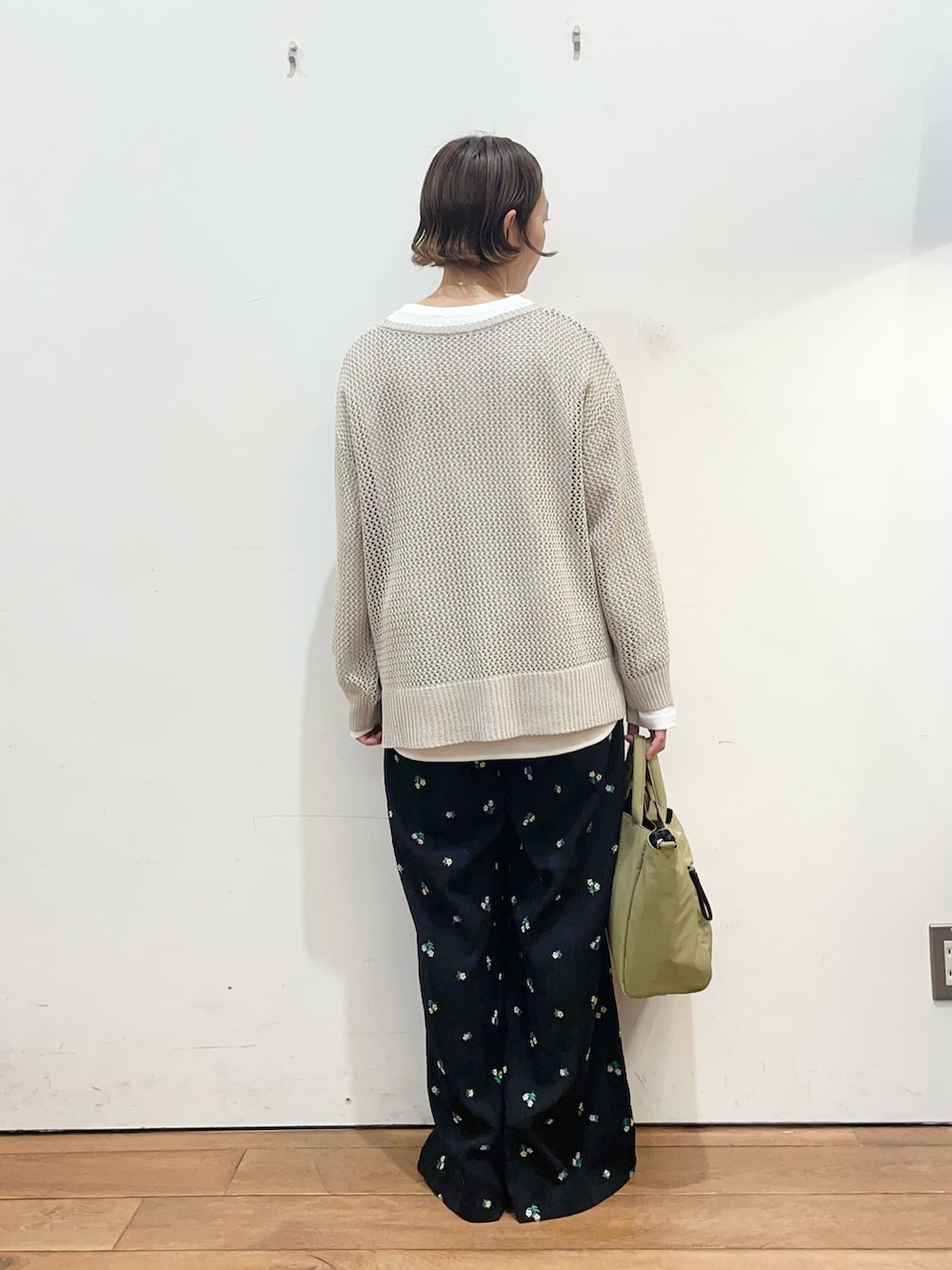 グレー系のニット/セーター、ホワイト系のTシャツ/カットソー、ベージュ系のトートバッグを着用したレディースの春コーディネートの4枚目の写真