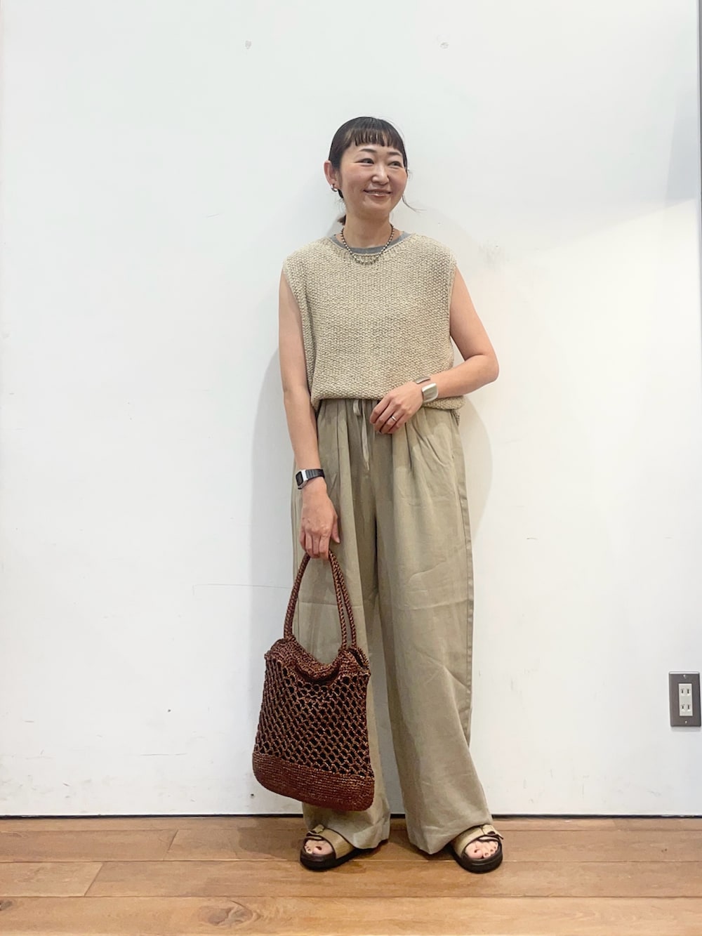 ベージュ系のニット/セーター、ベージュ系のサンダル、ブラウン系のトートバッグを着用したレディースの夏コーディネートの2枚目の写真