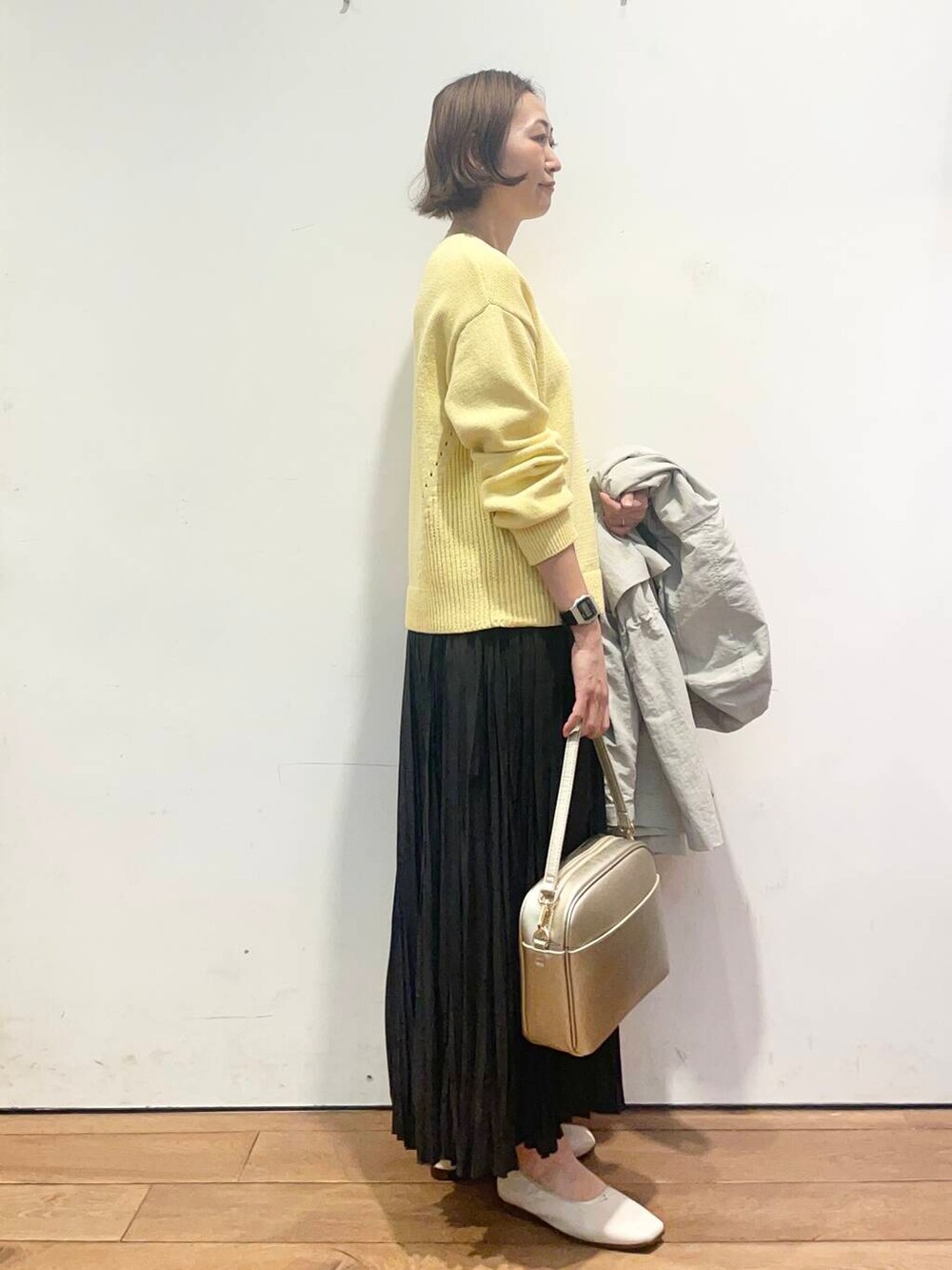 ゴールド系のショルダーバッグ、ブラック系のスカート、ホワイト系のバレエシューズを着用したレディースの春コーディネートの7枚目の写真