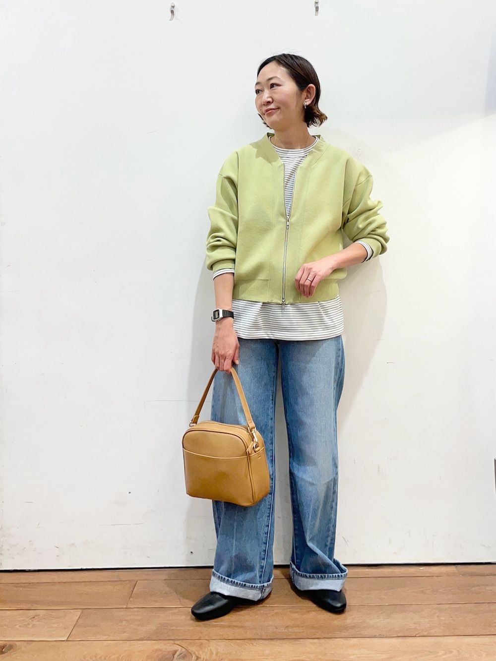 グリーン系のカーディガン/ボレロ、ホワイト系のTシャツ/カットソー、ブルー系のデニムパンツを着用したレディースの冬コーディネートの2枚目の写真