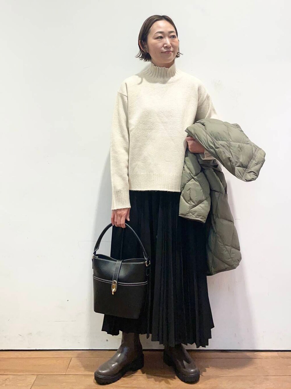 グリーン系のダウンジャケット/コート、ブラック系のハンドバッグ、ブラウン系のブーツを着用したレディースの冬コーディネートの6枚目の写真