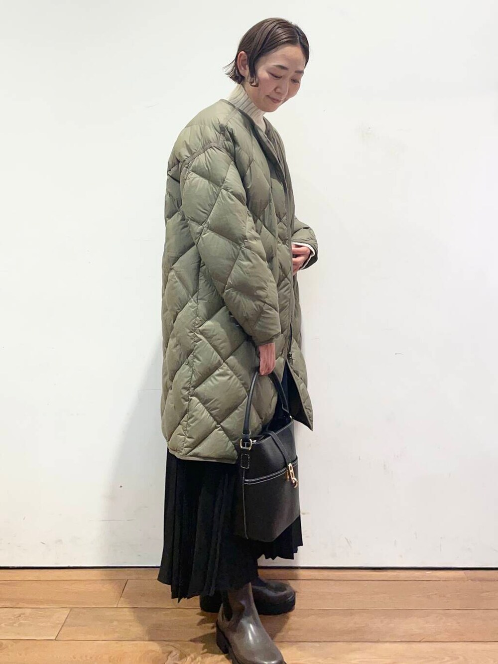 グリーン系のダウンジャケット/コート、ブラック系のハンドバッグ、ブラウン系のブーツを着用したレディースの冬コーディネートの3枚目の写真