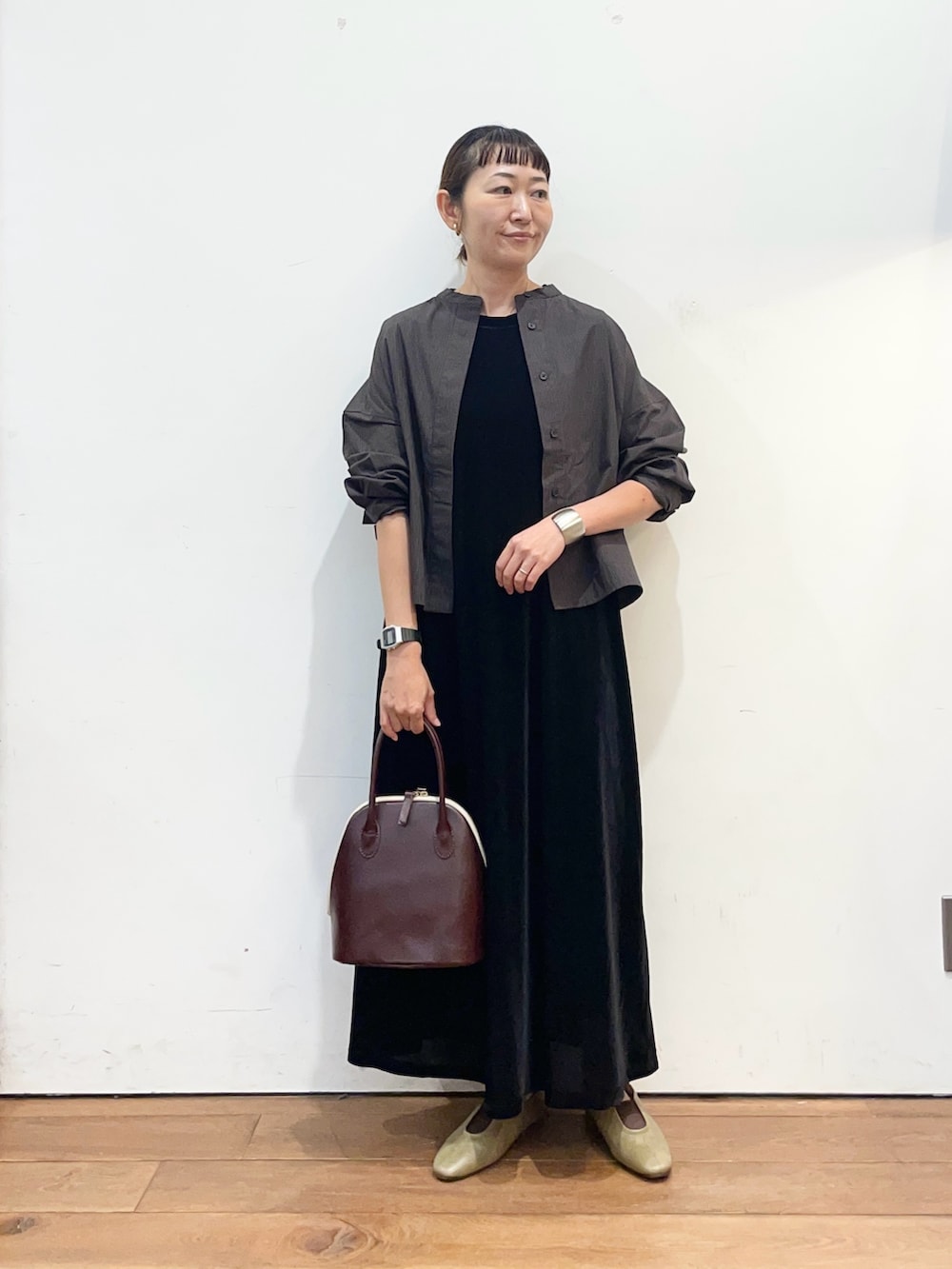 ブラック系のワンピース、ブラウン系のシャツ/ブラウス、レッド系のハンドバッグを着用したレディースの秋コーディネートの2枚目の写真