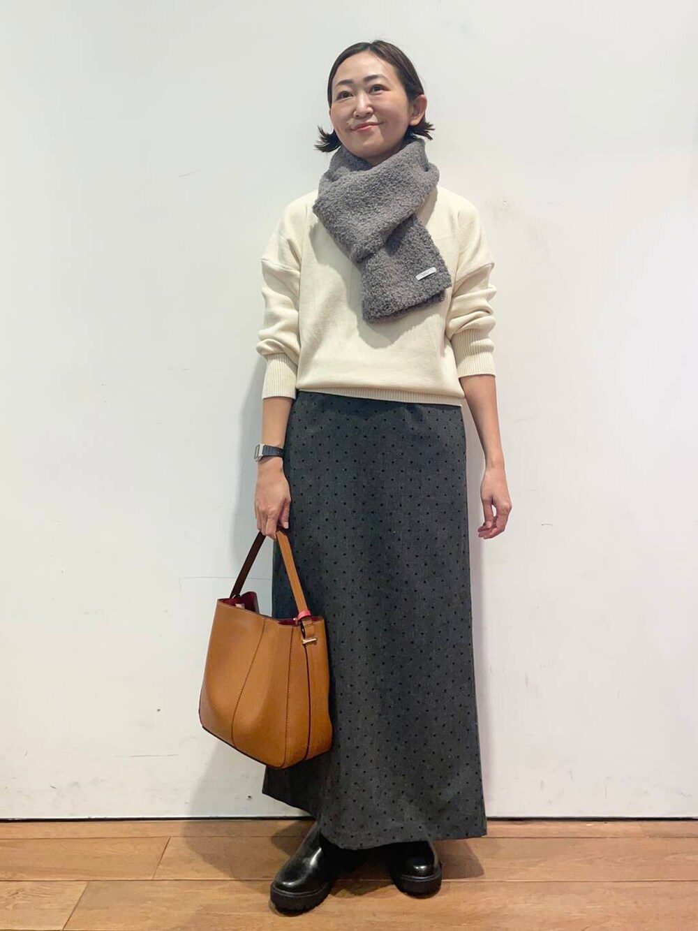 ブラウン系のハンドバッグ、ブラック系のブーツ、ホワイト系のニット/セーターを着用したレディースの秋コーディネートの3枚目の写真