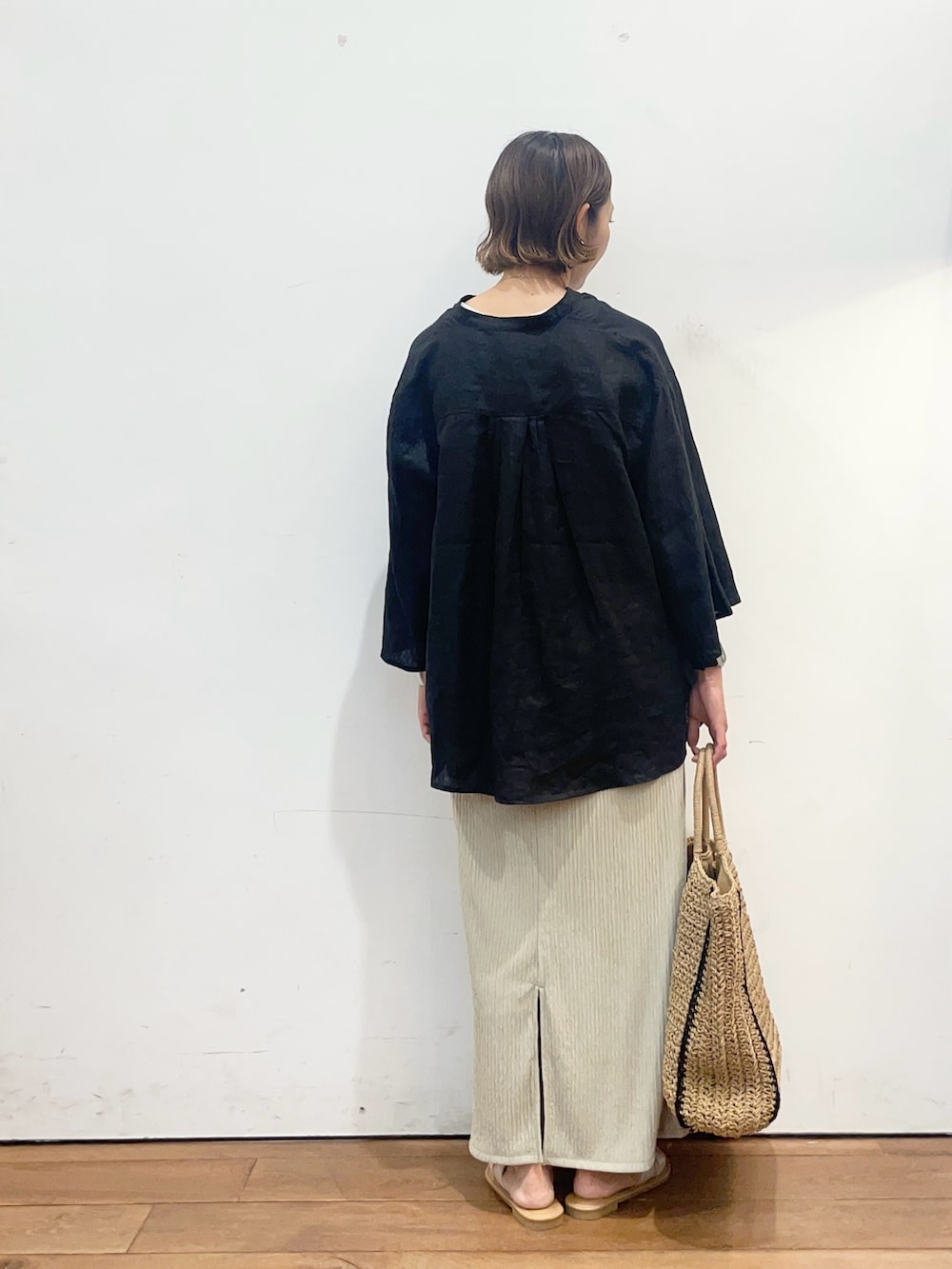 ブラック系のシャツ/ブラウス、ベージュ系のスカート、ベージュ系のトートバッグを着用したレディースの春コーディネートの4枚目の写真