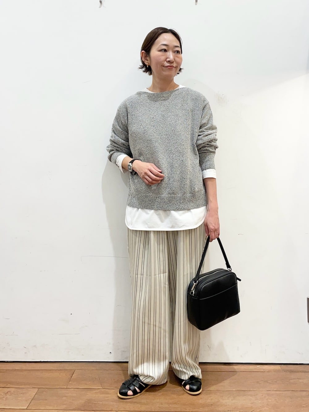 ブラック系のニット/セーター、ホワイト系のTシャツ/カットソー、ベージュ系のその他パンツを着用したレディースの春コーディネートの2枚目の写真