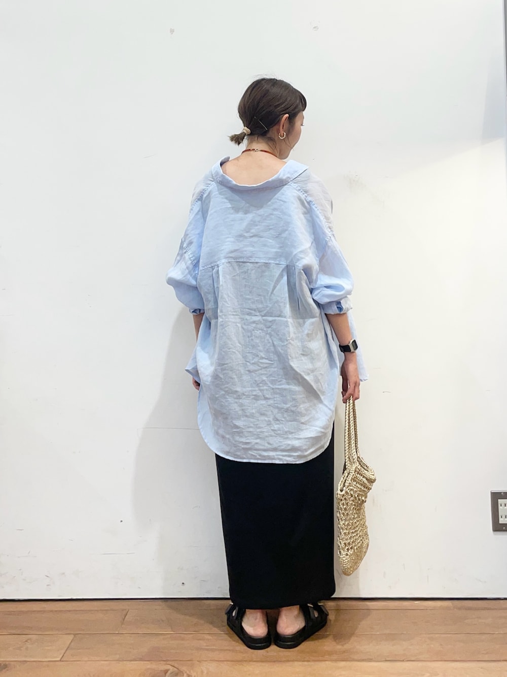 ブルー系のシャツ/ブラウス、ブラック系のワンピース、ゴールド系のトートバッグを着用したレディースの夏コーディネートの5枚目の写真