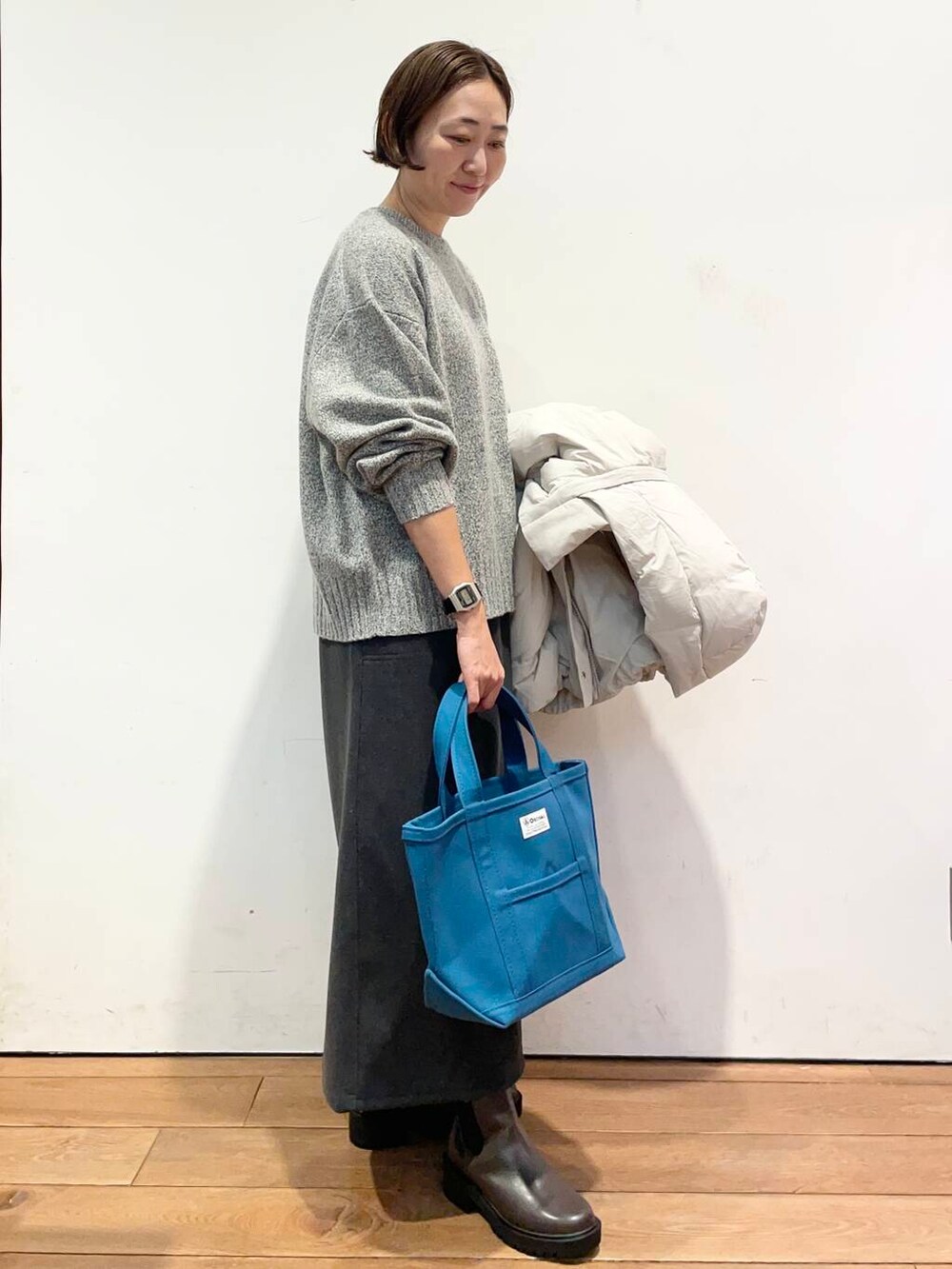 ホワイト系のダウンジャケット/コート、グレー系のニット/セーター、ブラウン系のブーツを着用したレディースの冬コーディネートの6枚目の写真