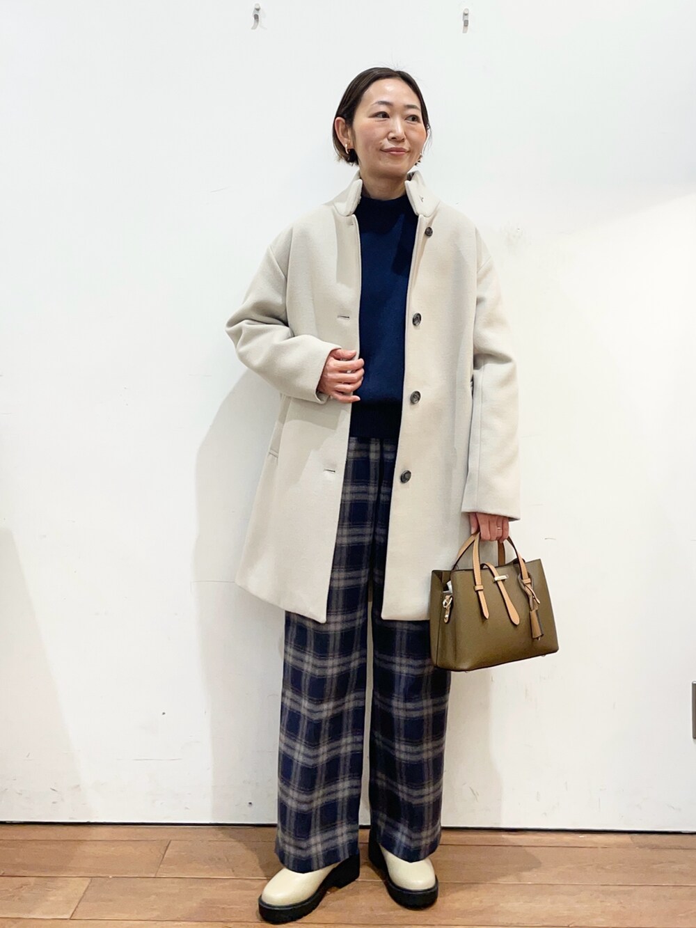 ベージュ系のその他アウター、ブルー系のニット/セーター、ブラウン系のハンドバッグを着用したレディースの冬コーディネートの2枚目の写真