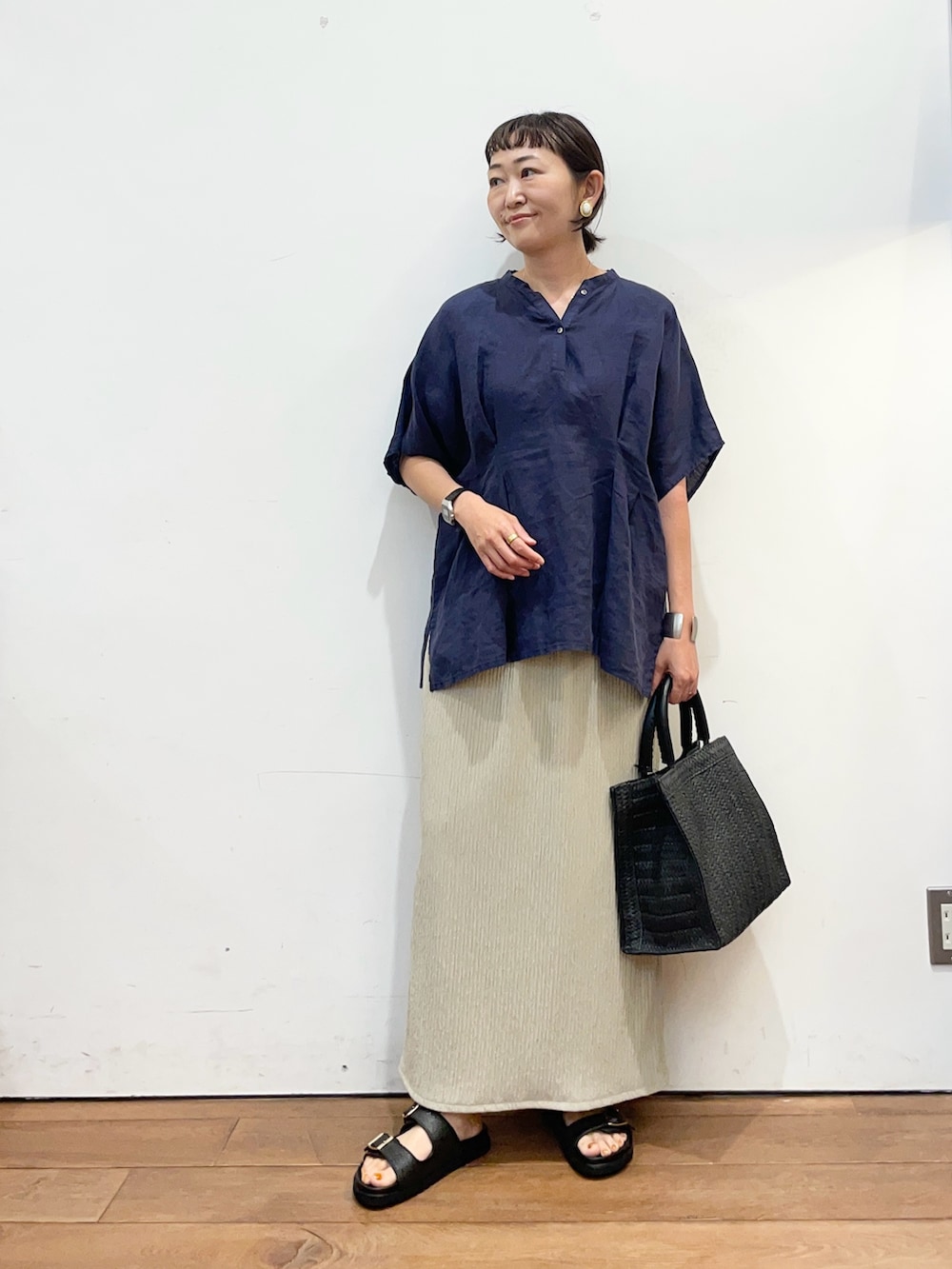 ブルー系のシャツ/ブラウス、ブラック系のハンドバッグ、ベージュ系のスカートを着用したレディースの夏コーディネートの2枚目の写真