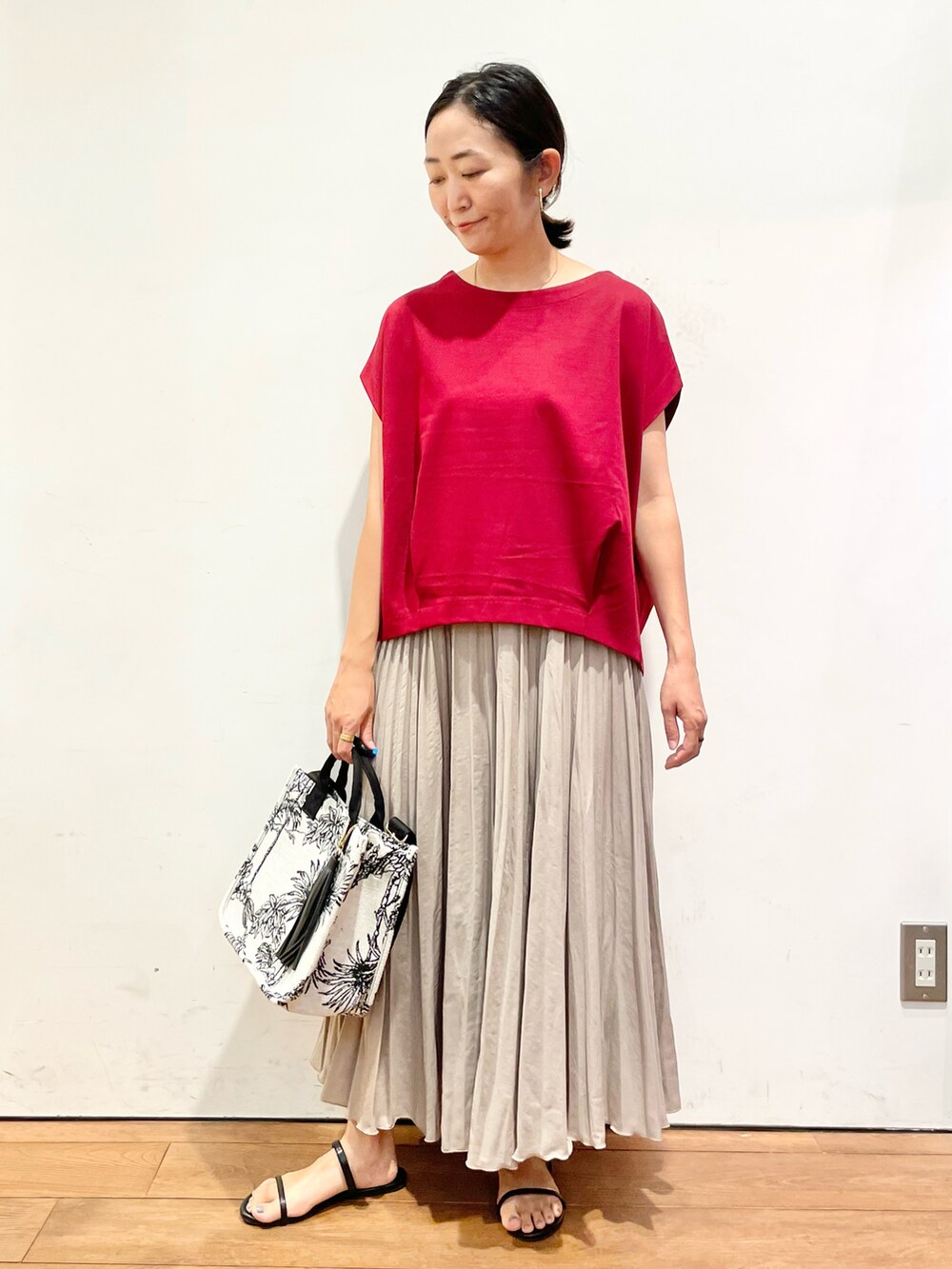 レッド系のTシャツ/カットソー、ベージュ系のスカート、ブラック系のサンダルを着用したレディースの夏コーディネートの2枚目の写真