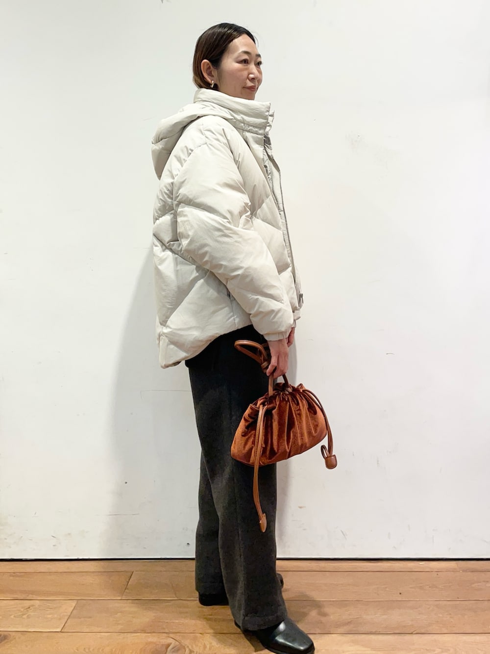 ホワイト系のダウンジャケット/コート、ブラウン系のニット/セーター、ブラック系のブーツを着用したレディースの秋コーディネートの3枚目の写真