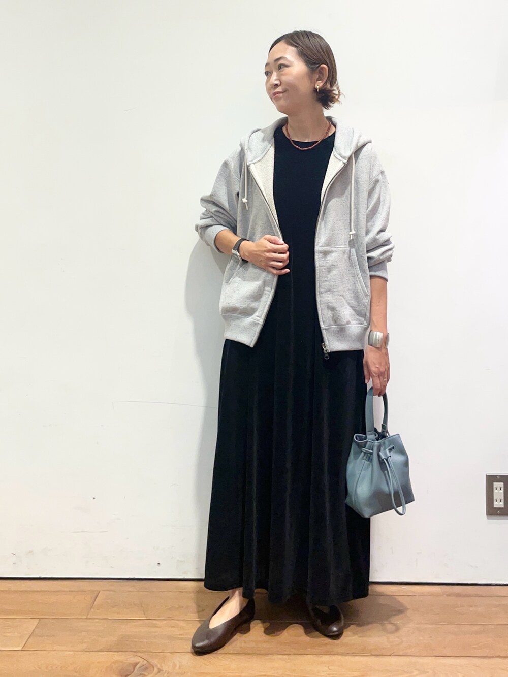 ブルー系のショルダーバッグ、ブラウン系のパンプス、ブラック系のワンピースを着用したレディースの秋コーディネートの2枚目の写真