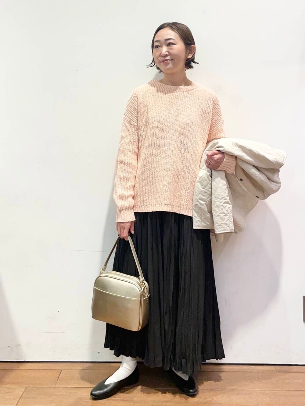 ゴールド系のショルダーバッグ、ブラック系のパンプス、ホワイト系のダウンジャケット/コートを着用したレディースの冬コーディネートの5枚目の写真