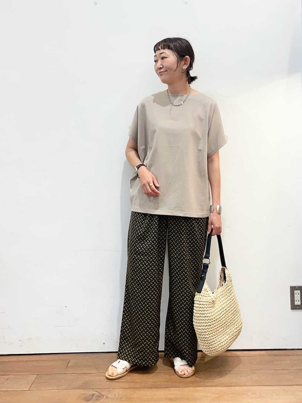 ベージュ系のトートバッグ、ホワイト系のサンダル、グレー系のTシャツ/カットソーを着用したレディースの夏コーディネートの2枚目の写真