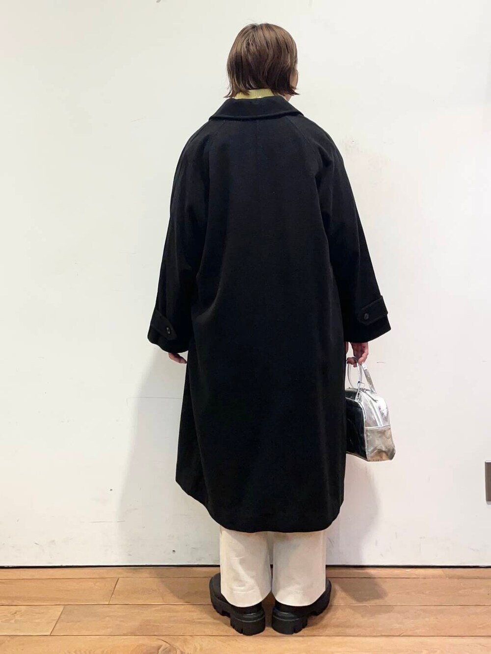 ブラック系のその他アウター、イエロー系のニット/セーター、ブラック系のブーツを着用したレディースの冬コーディネートの5枚目の写真