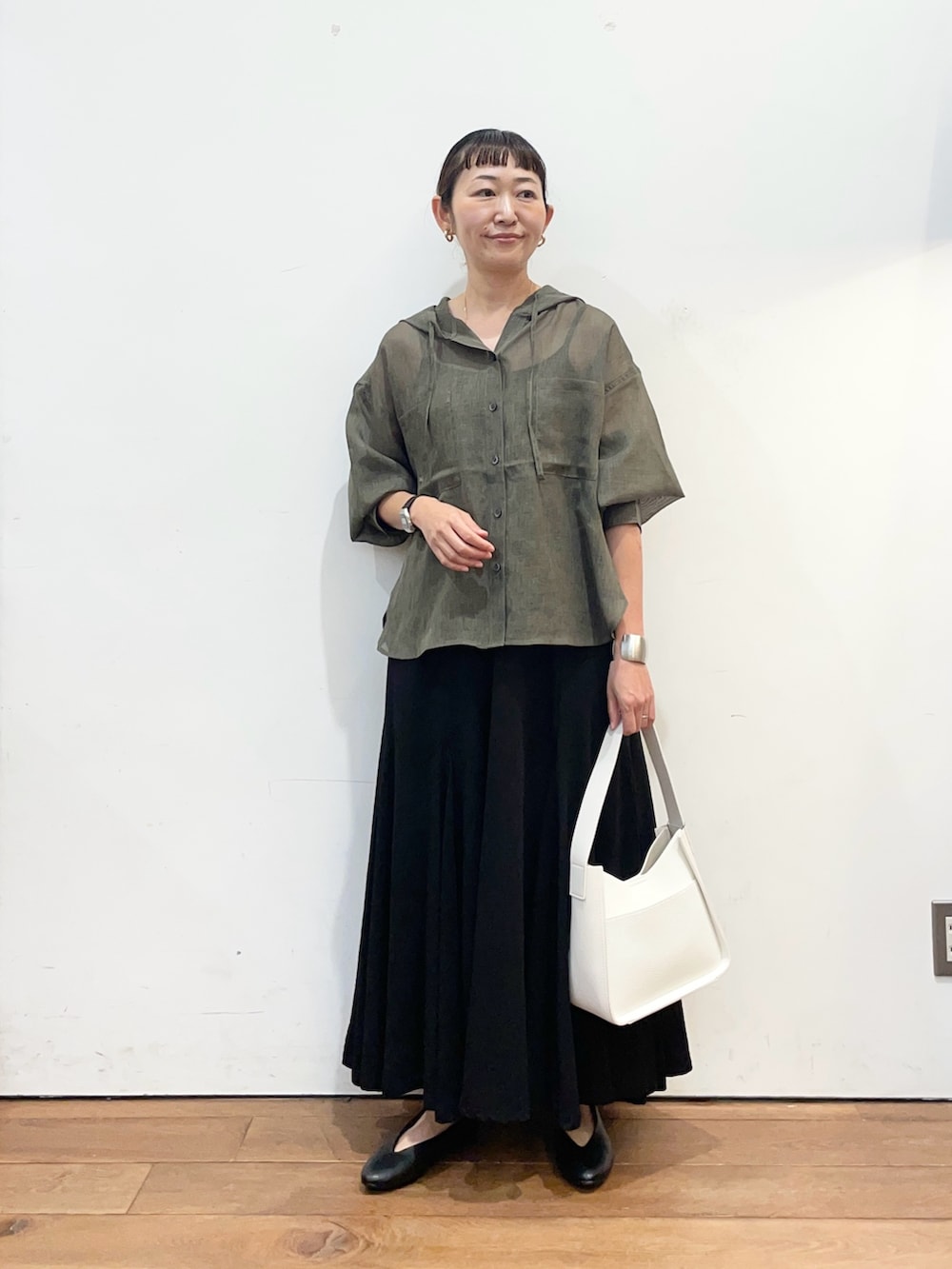 グレー系のシャツ/ブラウス、ブラック系のスカート、ホワイト系のハンドバッグを着用したレディースの秋コーディネートの2枚目の写真