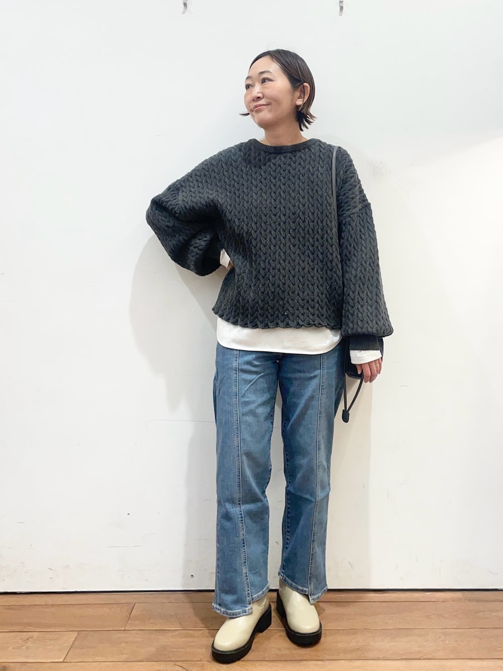 グレー系のニット/セーター、ホワイト系のTシャツ/カットソー、ブルー系のショルダーバッグを着用したレディースの冬コーディネートの3枚目の写真