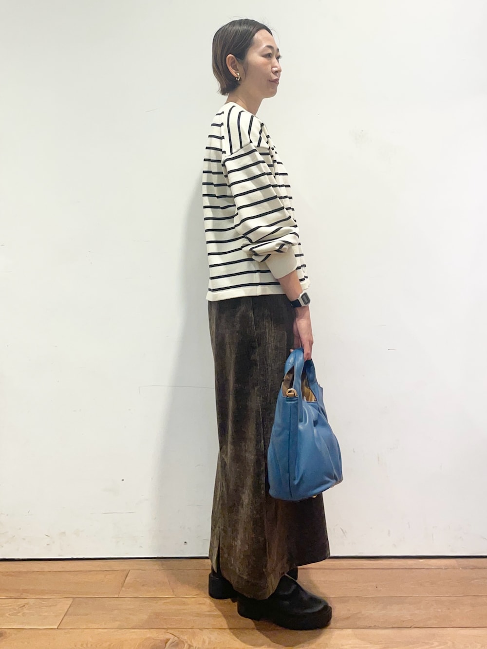 ホワイト系のカーディガン/ボレロ、ブラウン系のスカート、ブラック系のブーツを着用したレディースの秋コーディネートの4枚目の写真