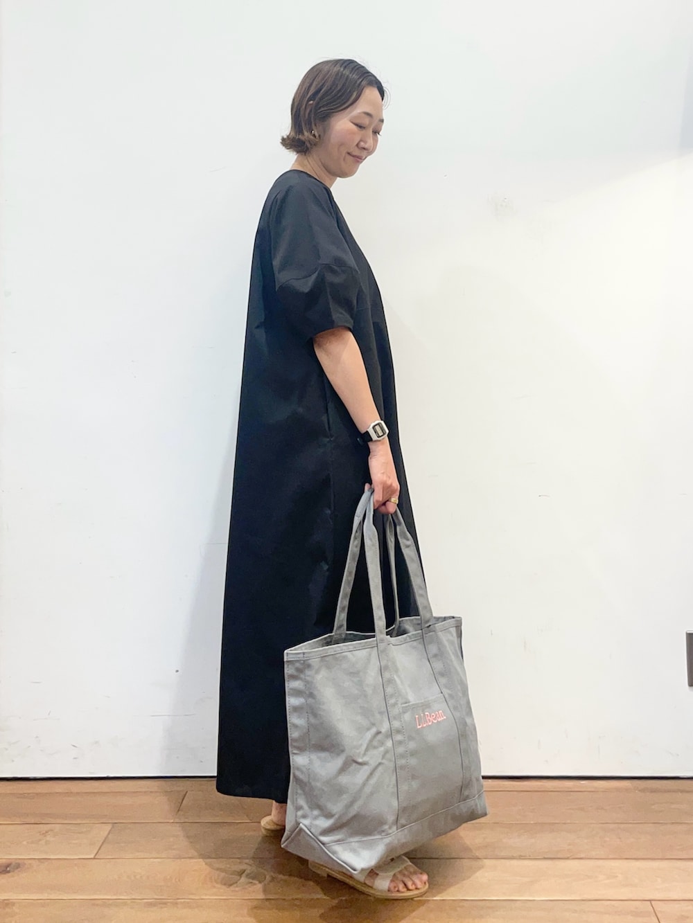 ブラック系のワンピース、ホワイト系のサンダル、グレー系のトートバッグを着用したレディースの春コーディネートの4枚目の写真