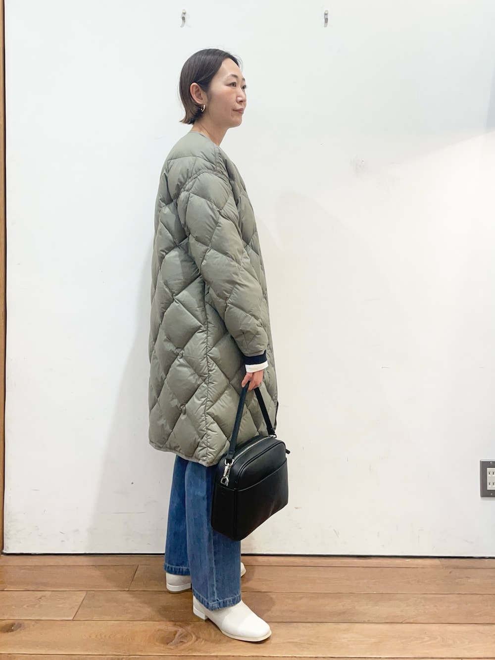 グリーン系のその他アウター、ホワイト系のブーツ、ブラック系のショルダーバッグを着用したレディースの冬コーディネートの3枚目の写真