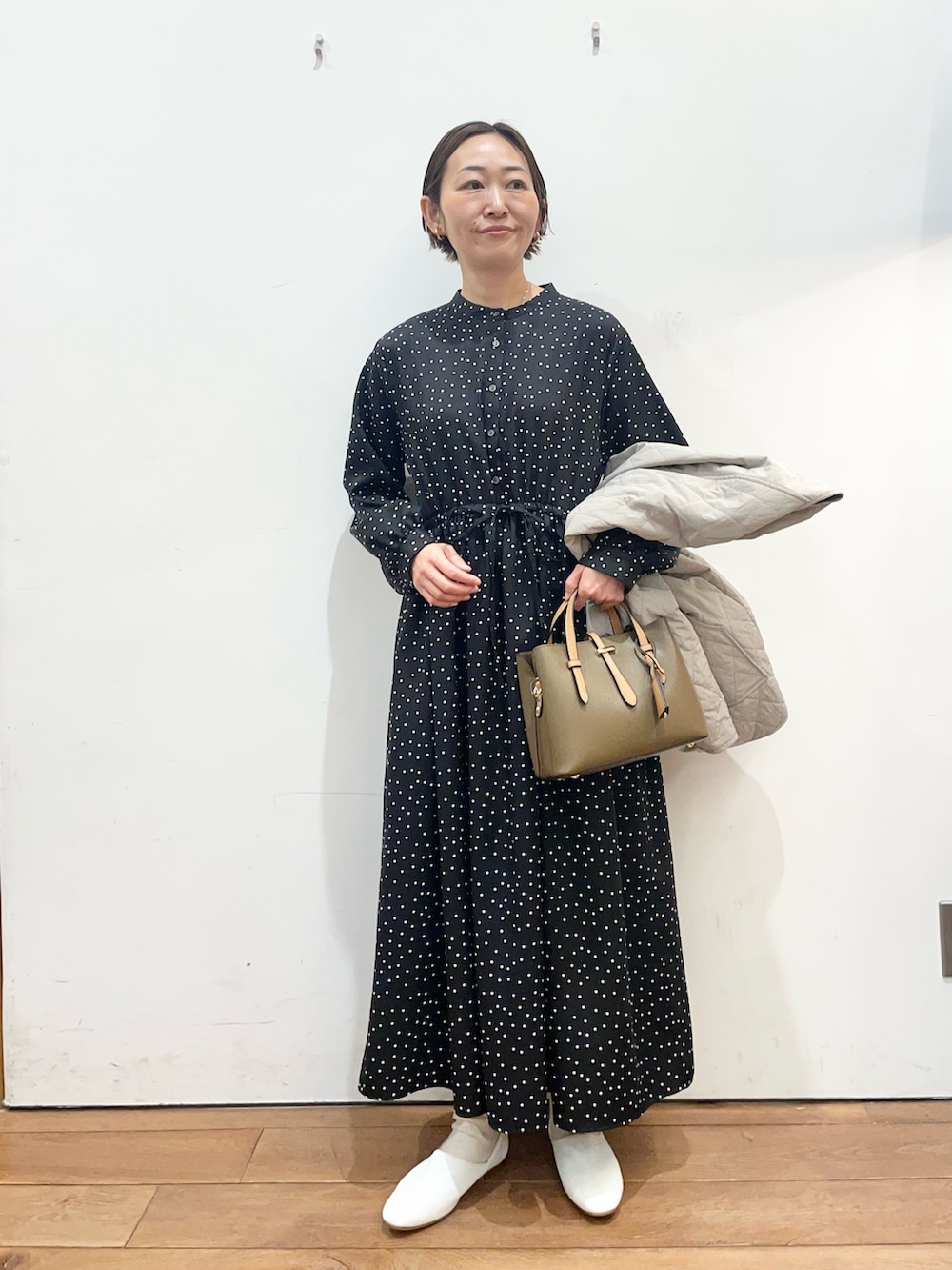 グレー系のダウンジャケット/コート、ホワイト系のその他シューズ、ブラック系のワンピースを着用したレディースの春コーディネートの6枚目の写真