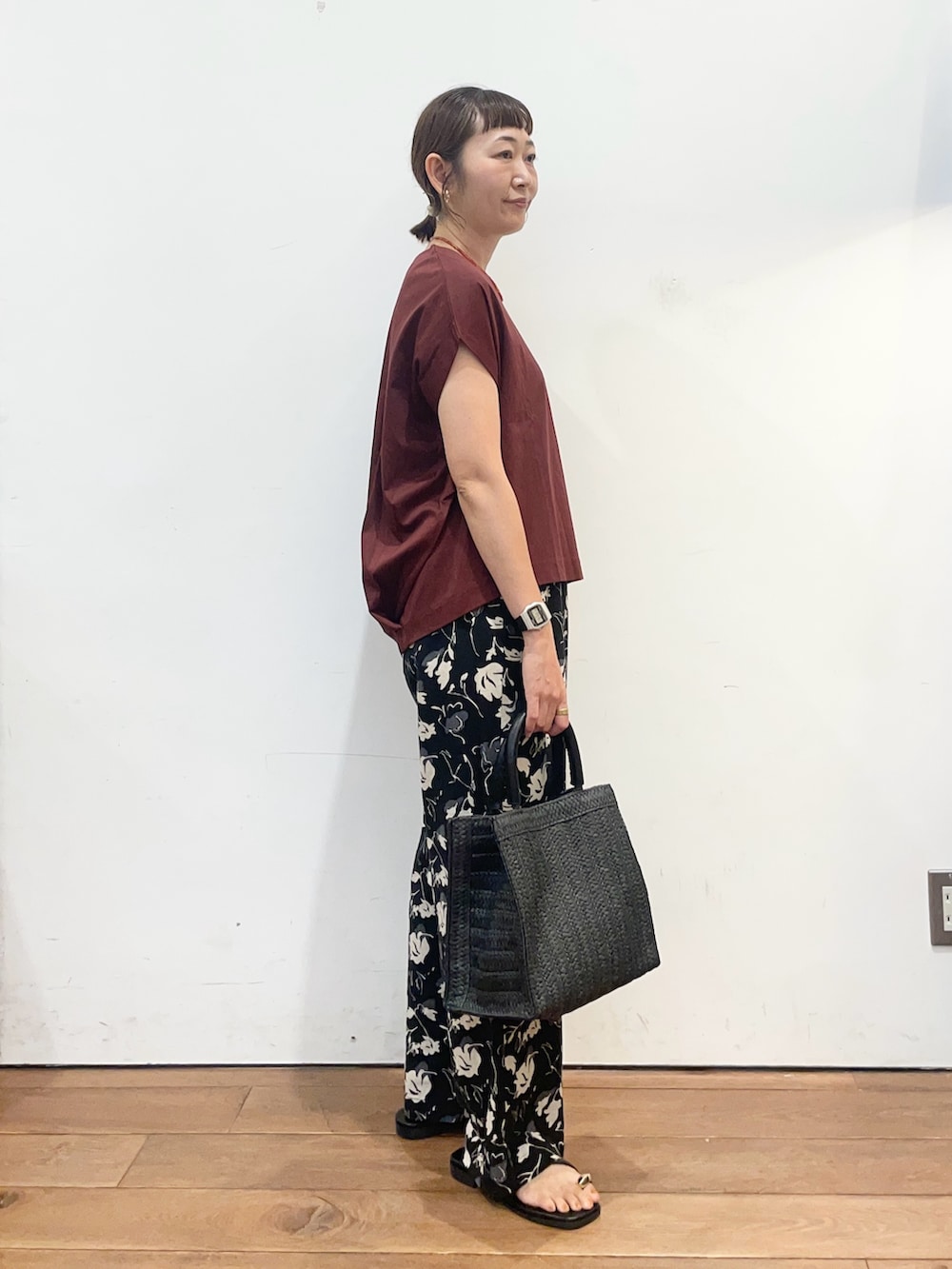 レッド系のTシャツ/カットソー、ブラック系のサンダル、ブラック系のハンドバッグを着用したレディースの夏コーディネートの3枚目の写真