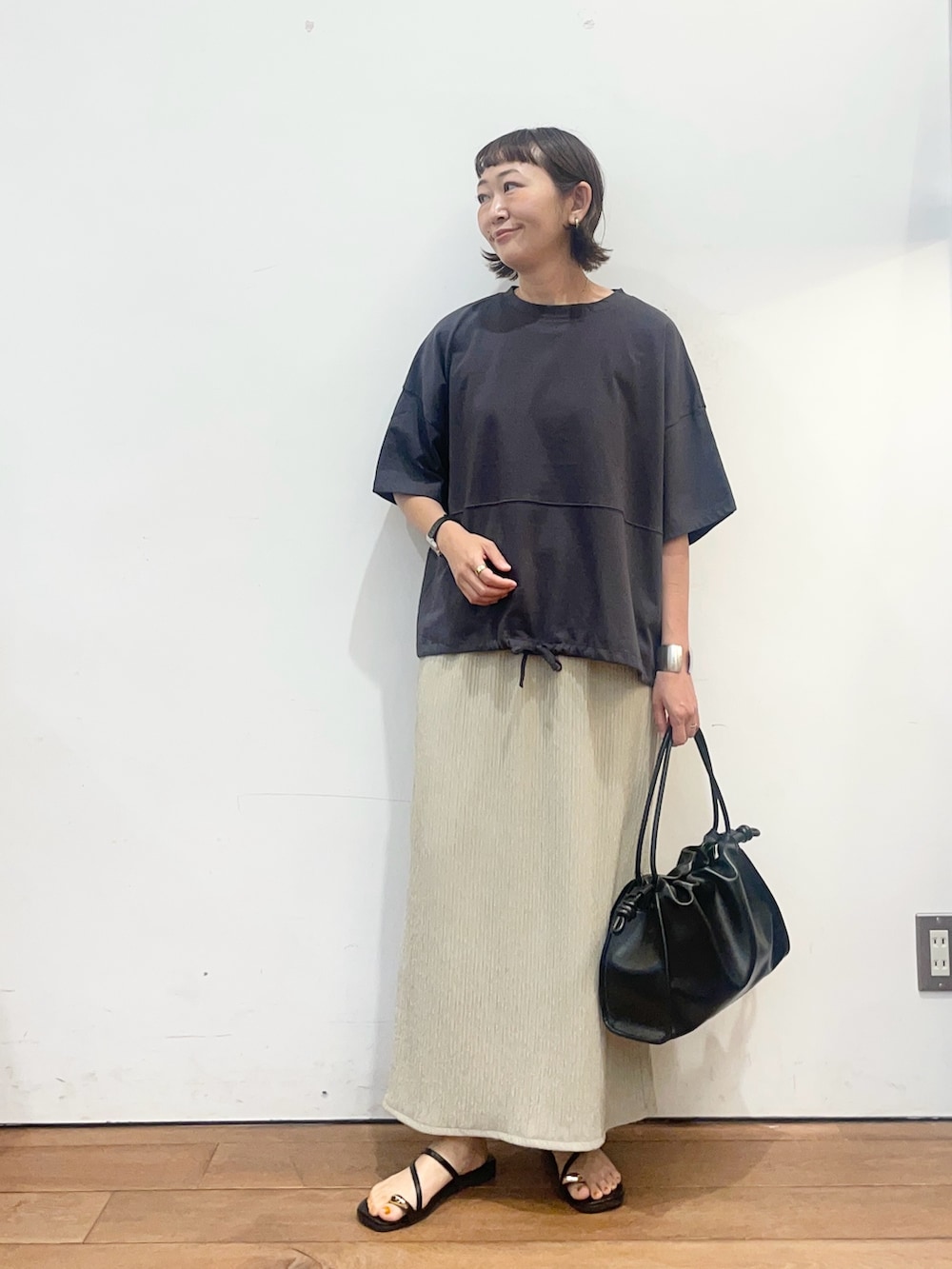 グレー系のTシャツ/カットソー、ベージュ系のスカート、ブラック系のトートバッグを着用したレディースの夏コーディネートの2枚目の写真