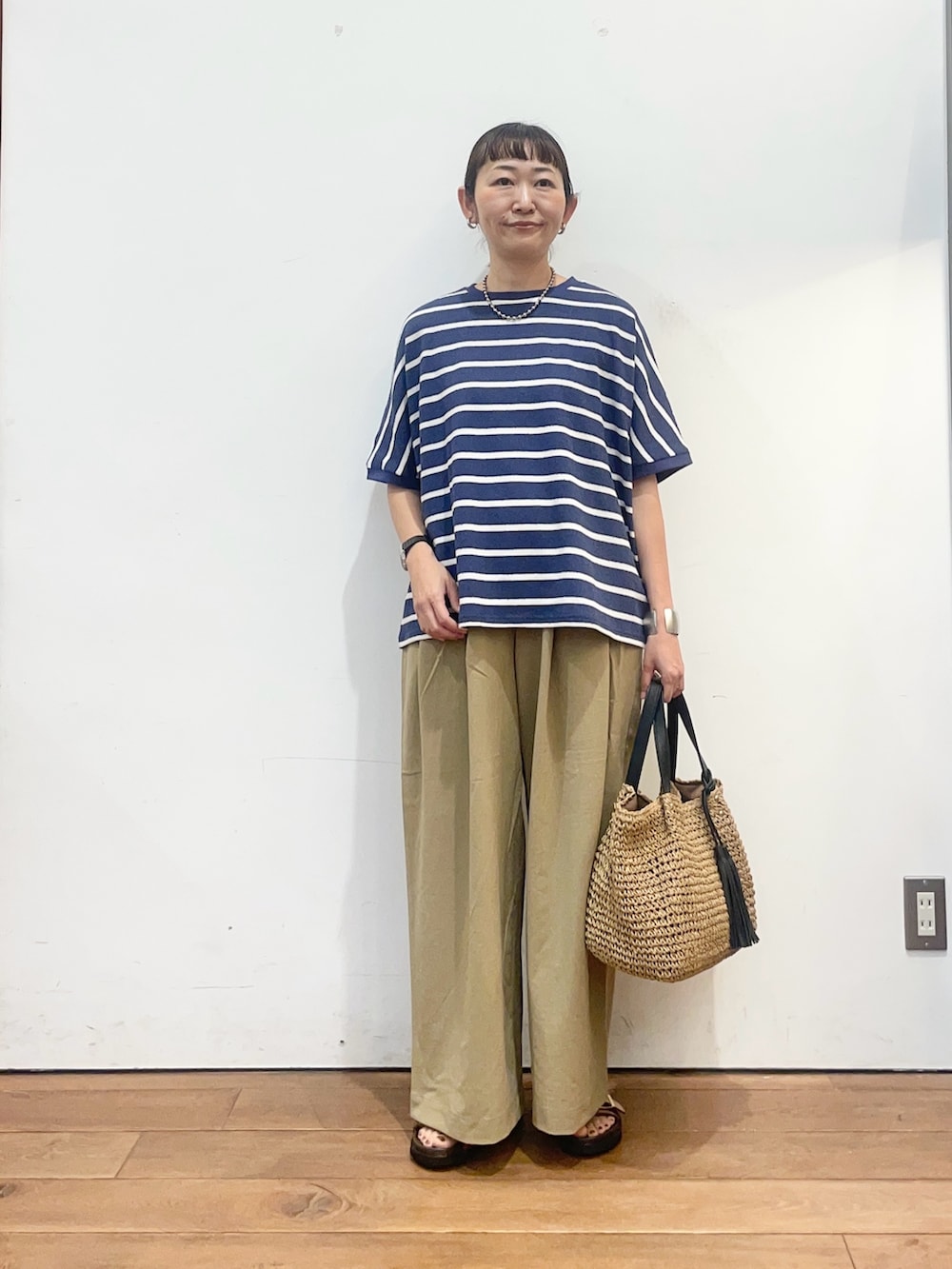 ブルー系のTシャツ/カットソー、ベージュ系のサンダル、イエロー系のかごバッグを着用したレディースの夏コーディネートの2枚目の写真