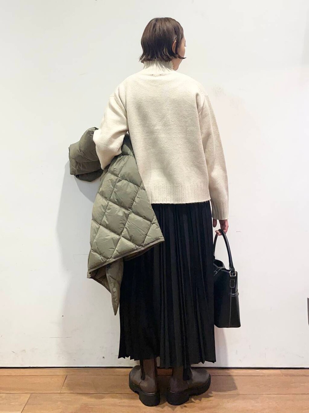 グリーン系のダウンジャケット/コート、ブラック系のハンドバッグ、ブラウン系のブーツを着用したレディースの冬コーディネートの7枚目の写真