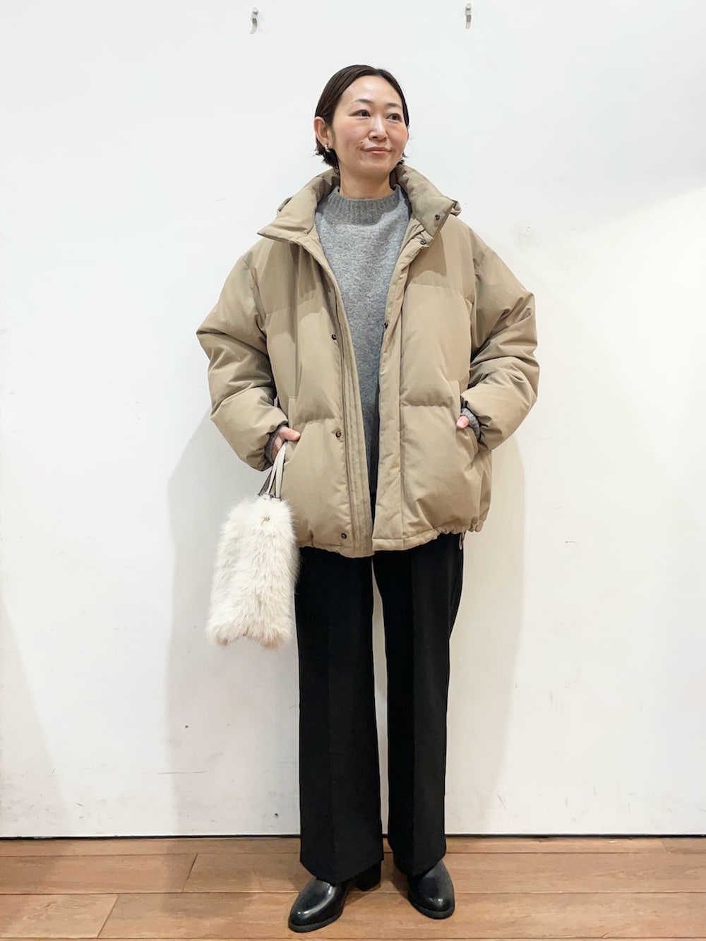 ブラウン系のダウンジャケット/コート、グレー系のニット/セーター、ブラック系のブーツを着用したレディースの冬コーディネートの2枚目の写真