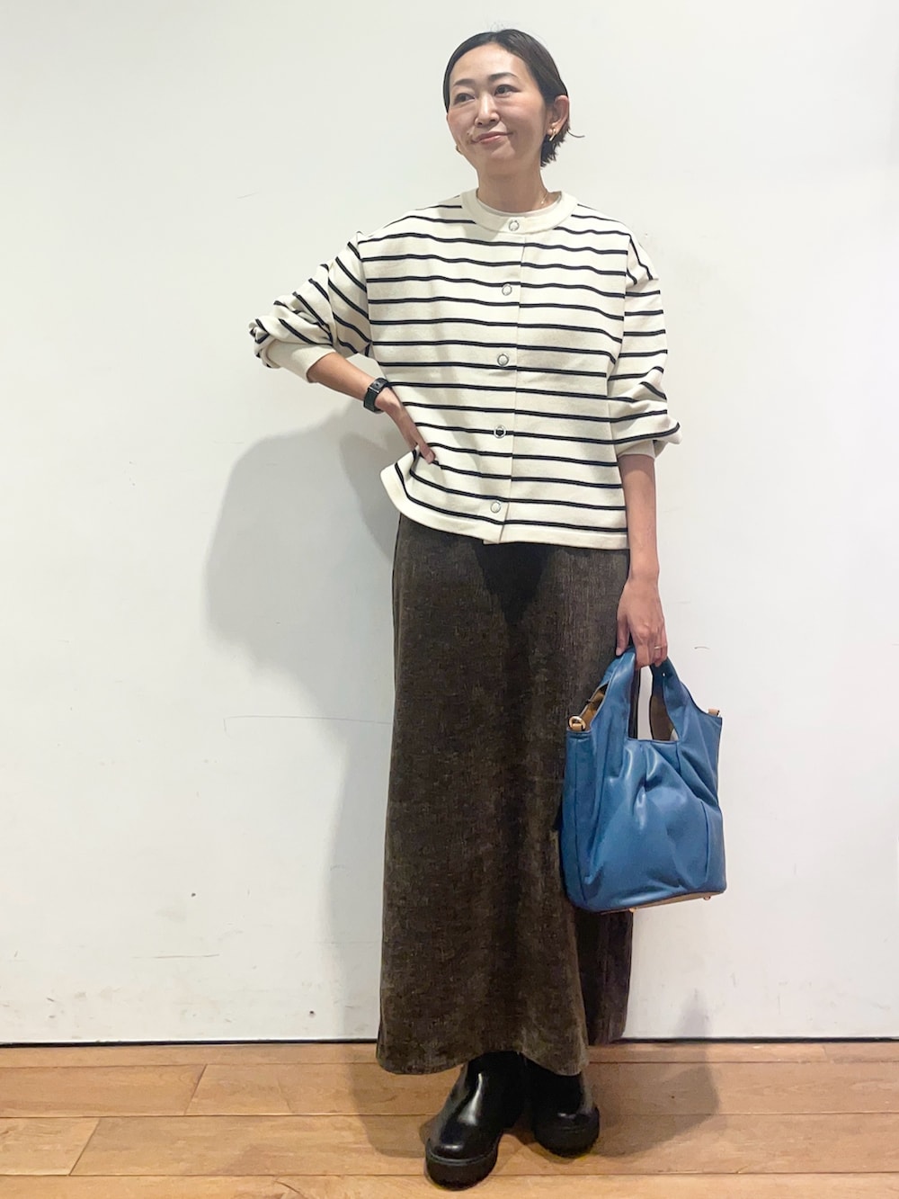 ホワイト系のカーディガン/ボレロ、ブラウン系のスカート、ブラック系のブーツを着用したレディースの秋コーディネートの2枚目の写真