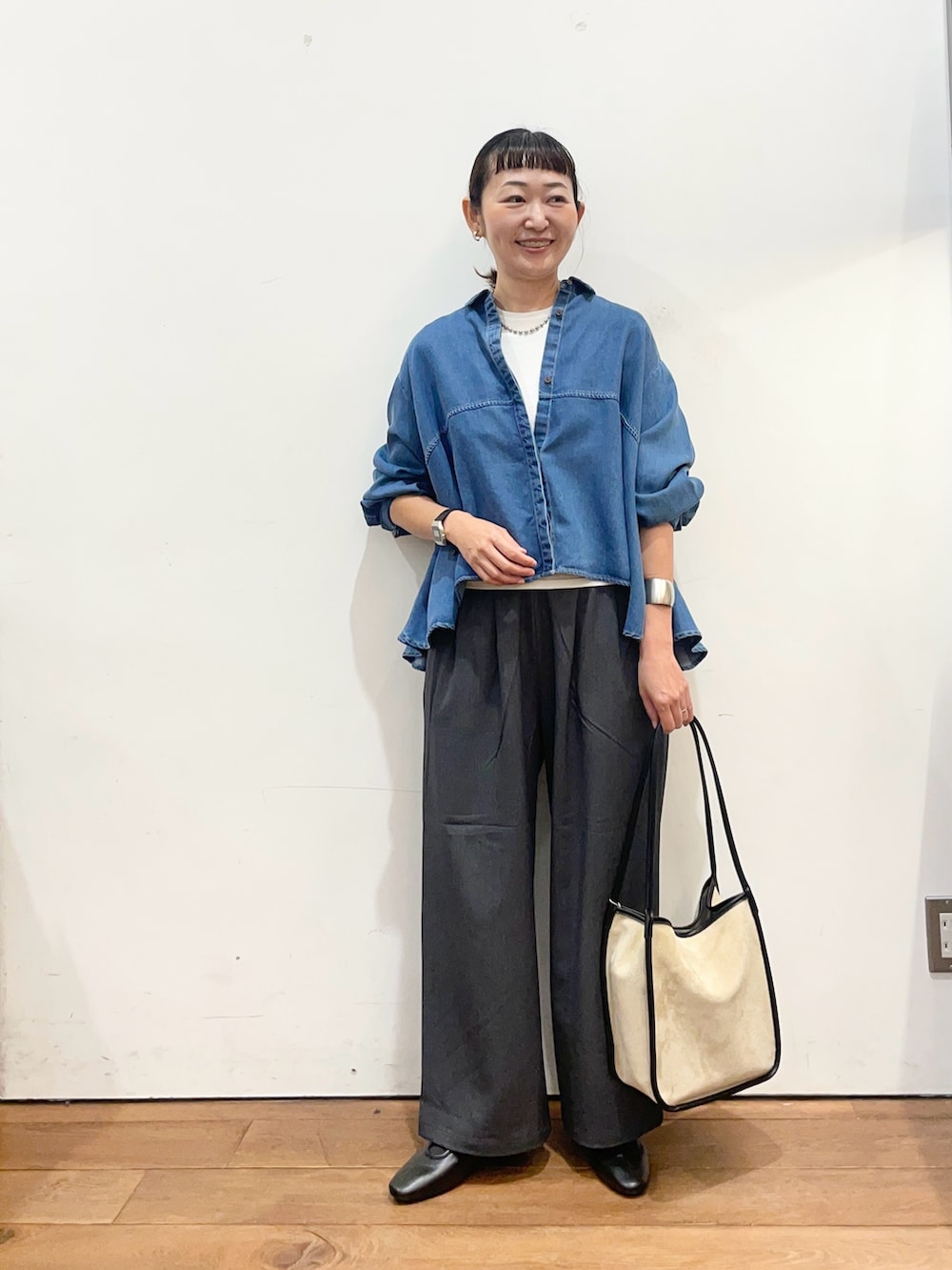 ブルー系のシャツ/ブラウス、ベージュ系のトートバッグ、ブラック系のスリッポンを着用したレディースの秋コーディネートの2枚目の写真